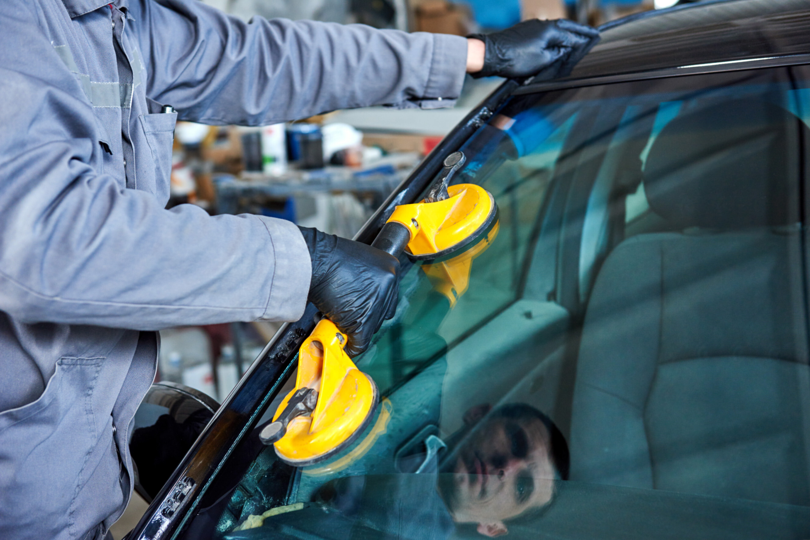 Professional inspecting and repairing a damaged car windscreen, showcasing expert windscreen repair and replacement services near you.