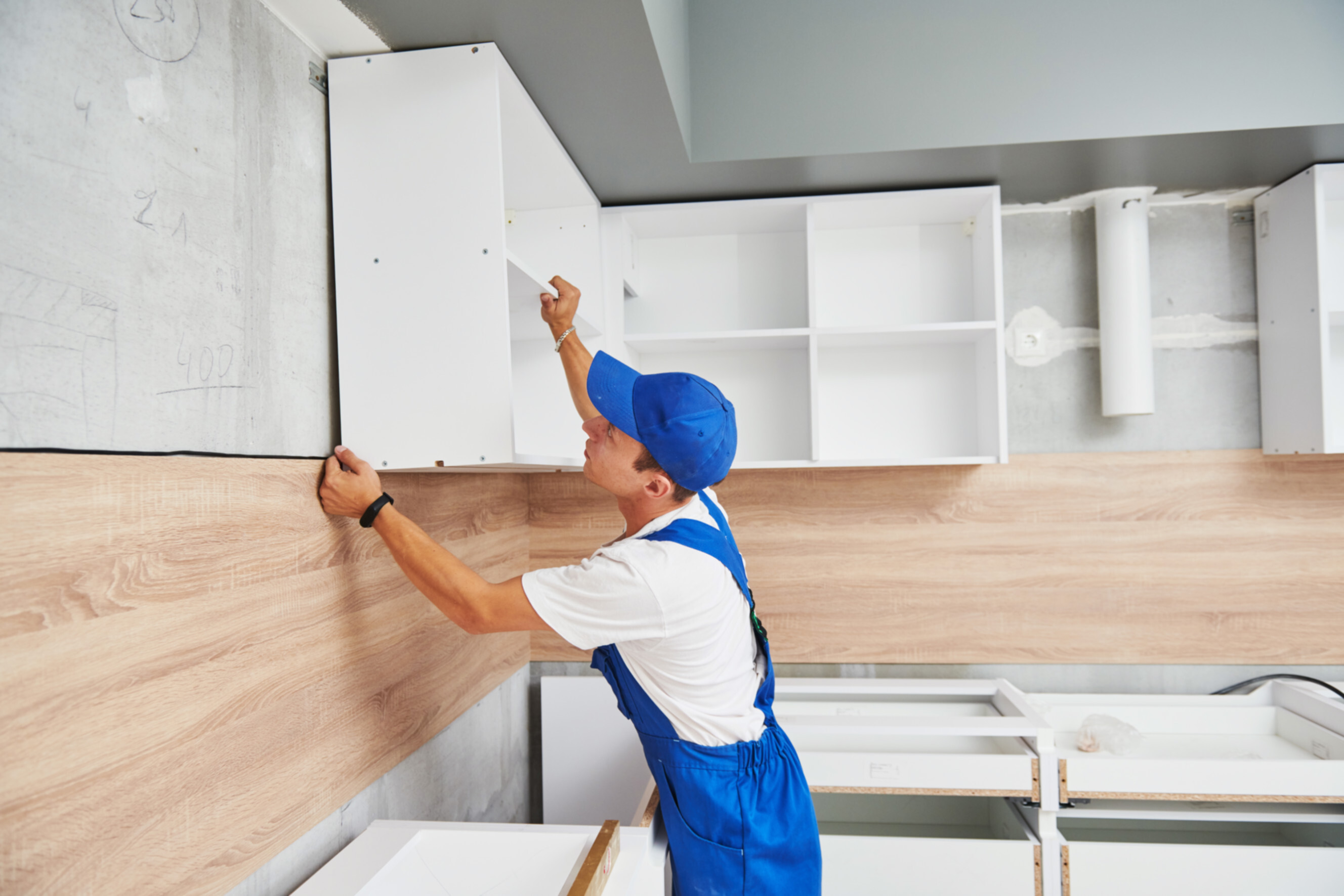 Skilled cabinet maker installing custom-built cabinets in a modern kitchen, showcasing expert cabinet makers near you.