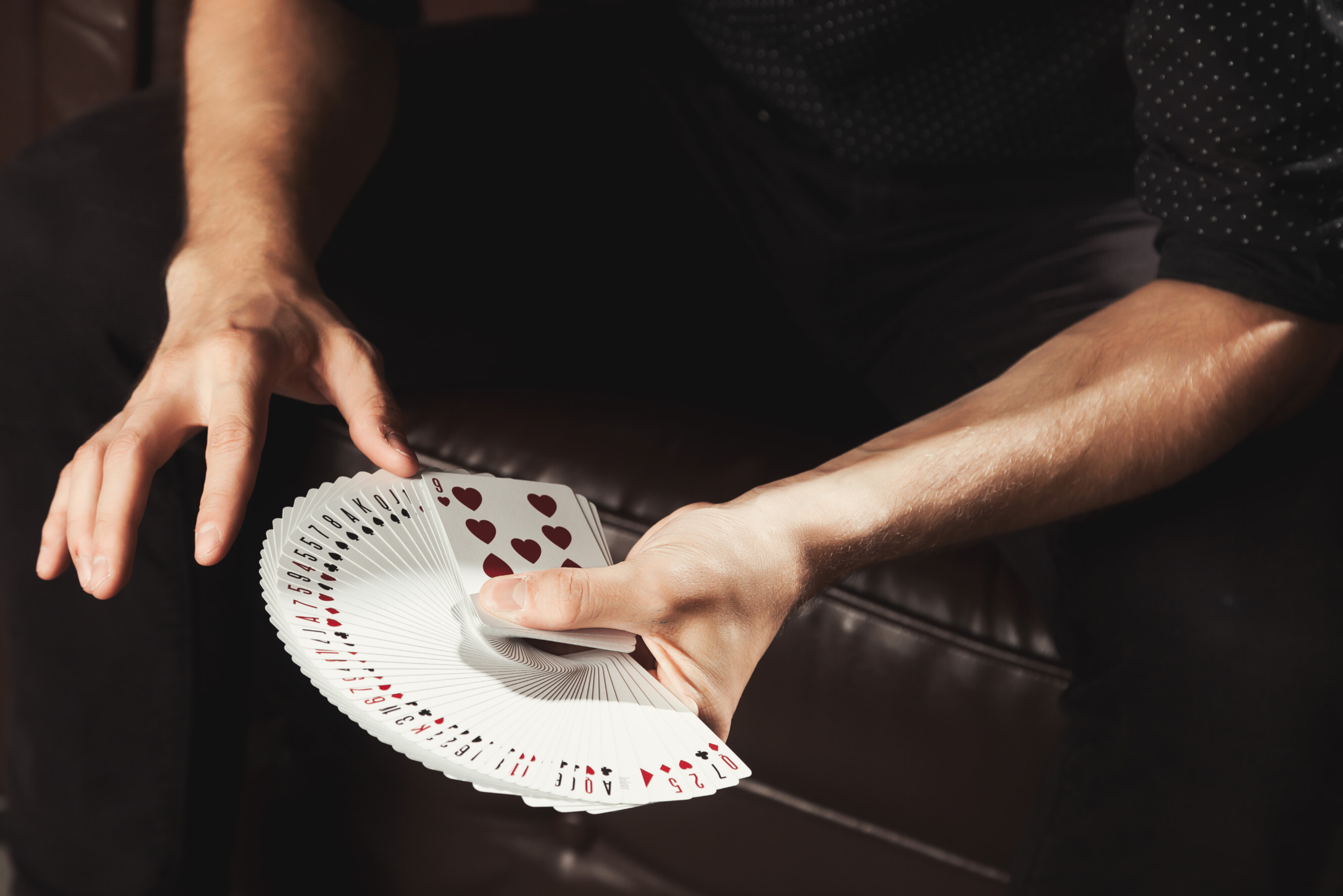 Magician performing a card trick with a perfectly fanned deck of cards, showcasing skilled magicians near you.