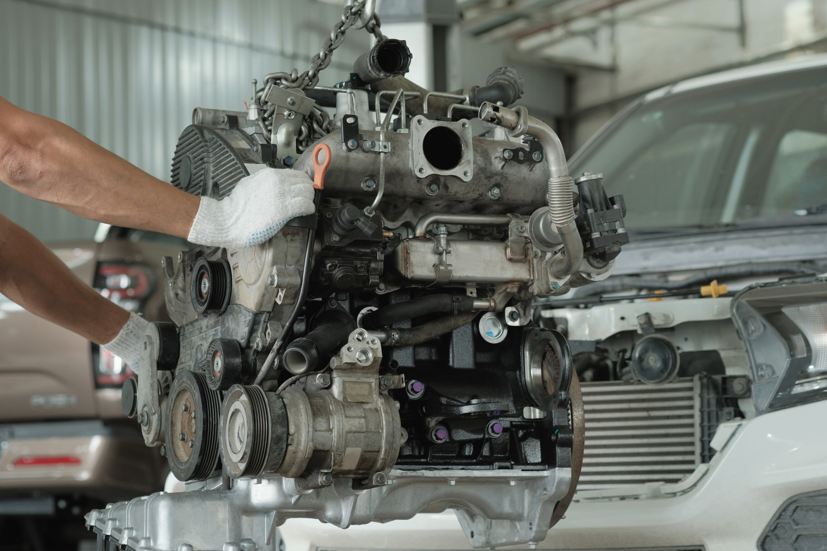 Mechanic carefully handling a car engine during a replacement process, highlighting expert car engine replacement services near you.