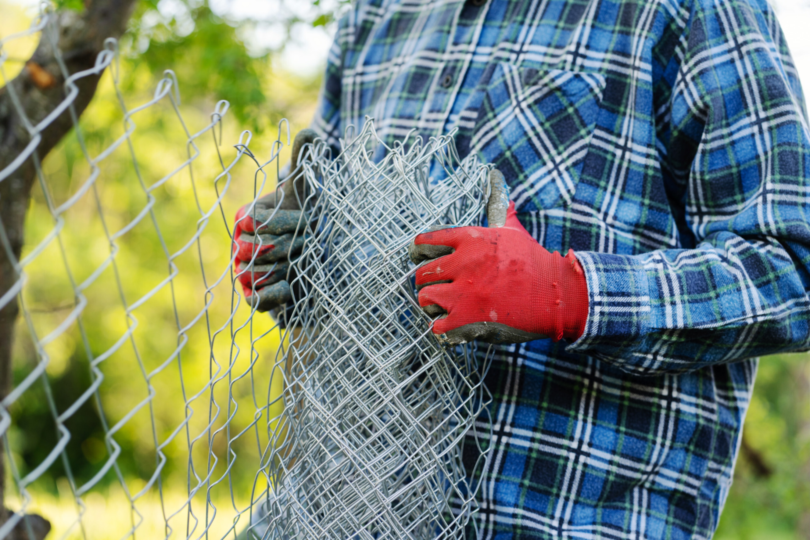 Expert installing a chain link fence in an outdoor setting, highlighting professional chain link fence services near you.