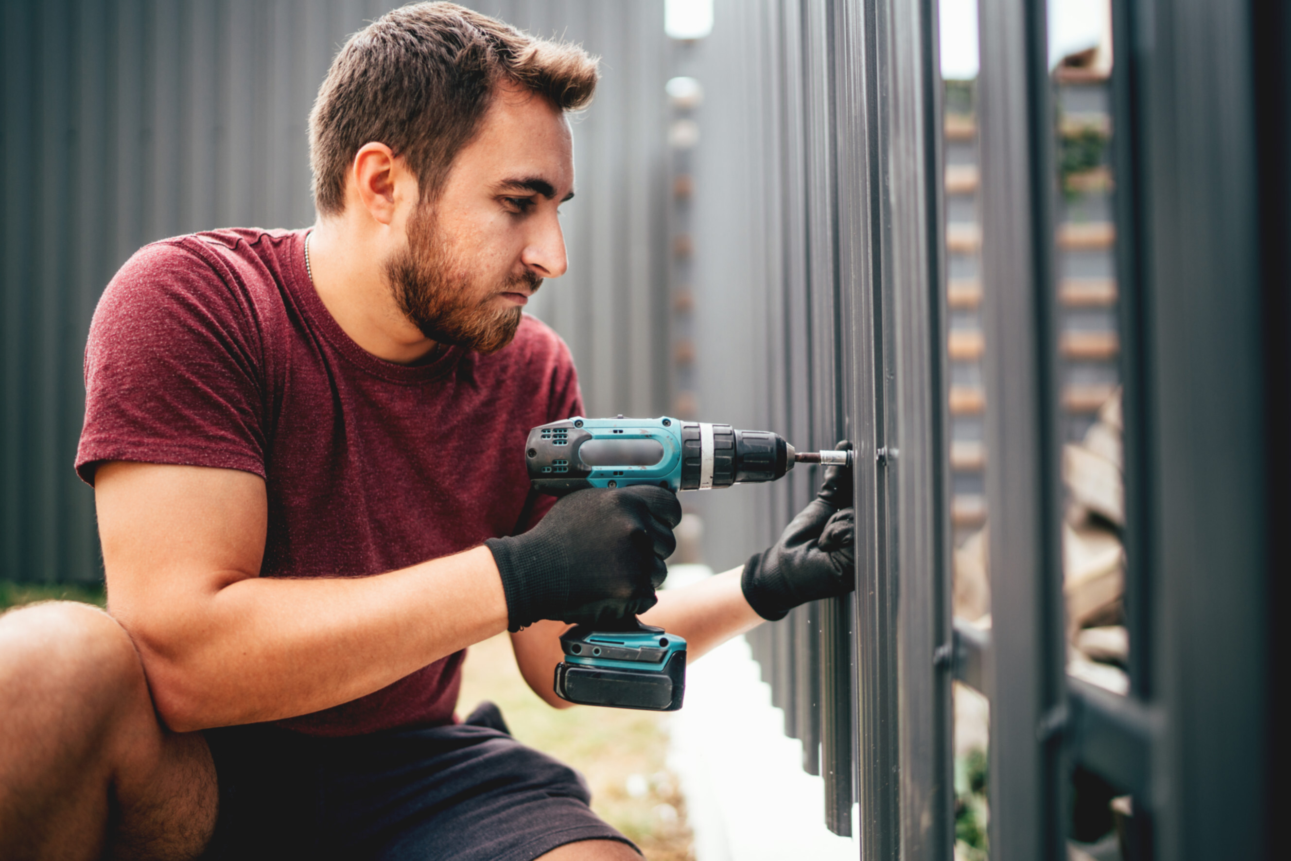 Professional installing a metal fence using a power drill, showcasing expert fence installation services near you.