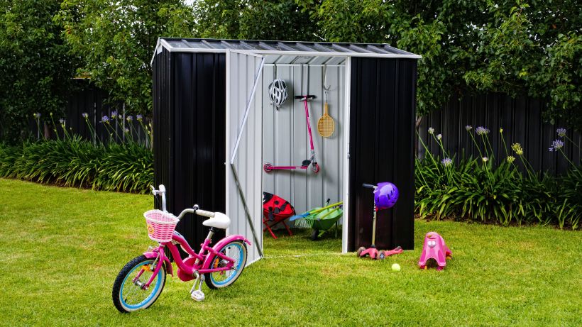 A compact and stylish black garden shed by Easyshed, set in a lush green backyard