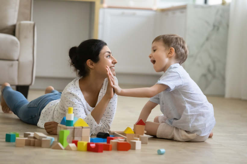 Nanny vs babysitter - A babysitter playing happily with a child using colorful building blocks