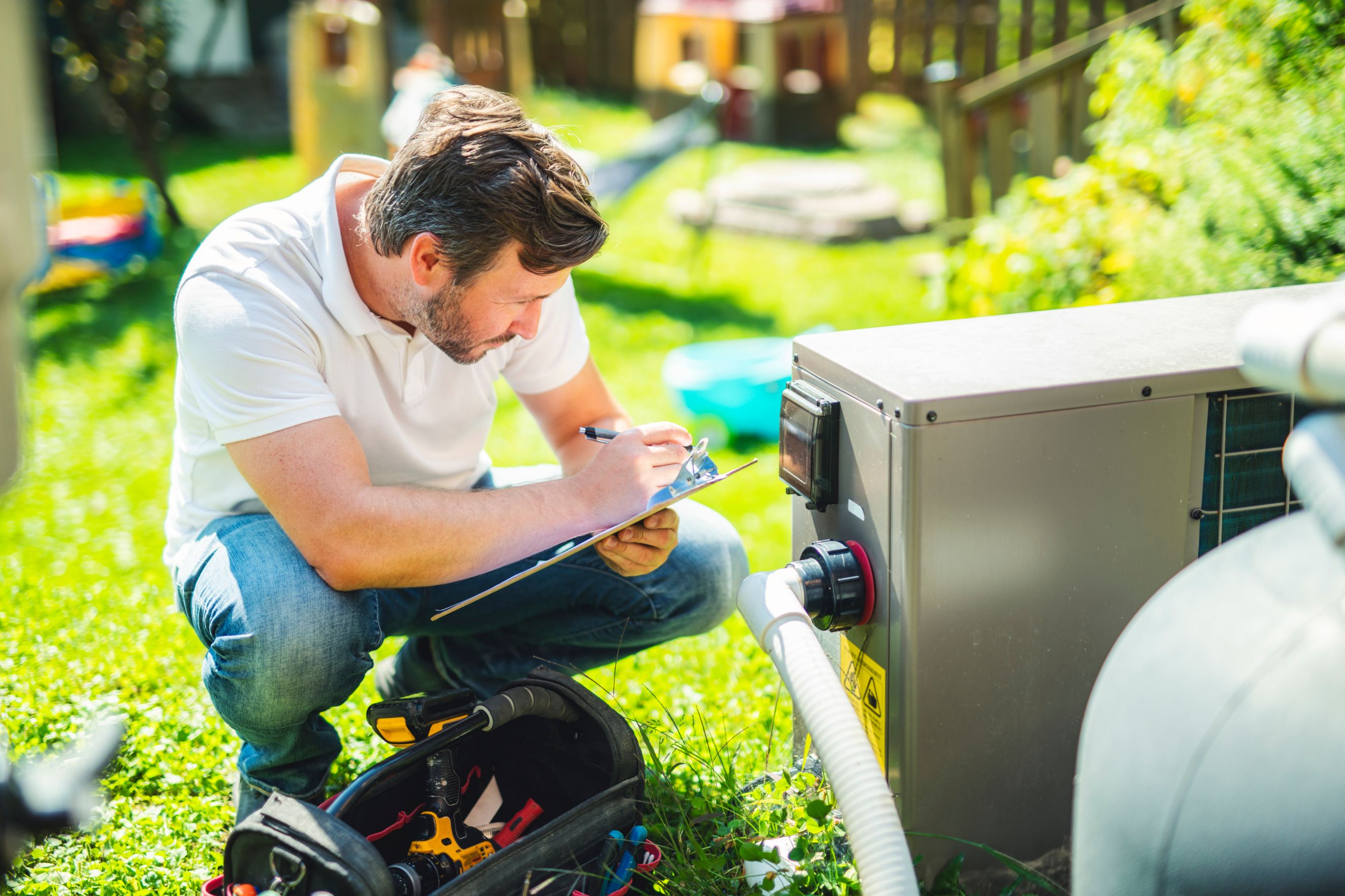 An electrician working on pool heater installation outdoors.