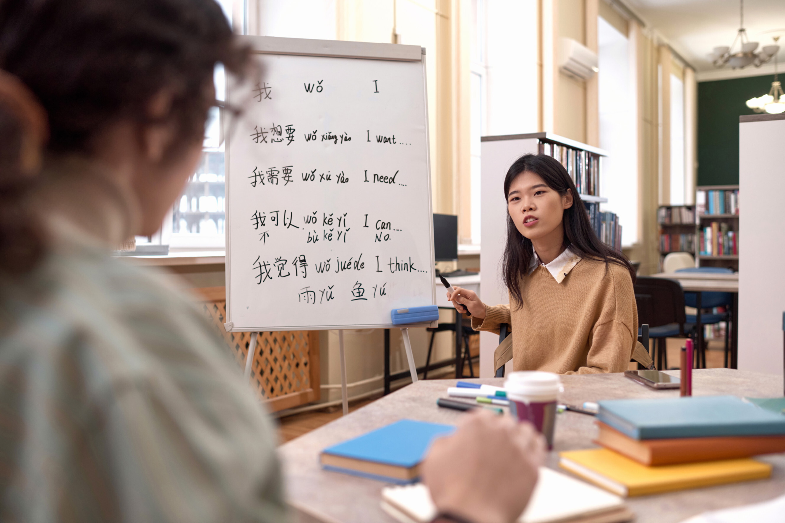 Chinese tutor teaching a student with a whiteboard displaying Mandarin phrases, highlighting professional Chinese tutoring services near you.