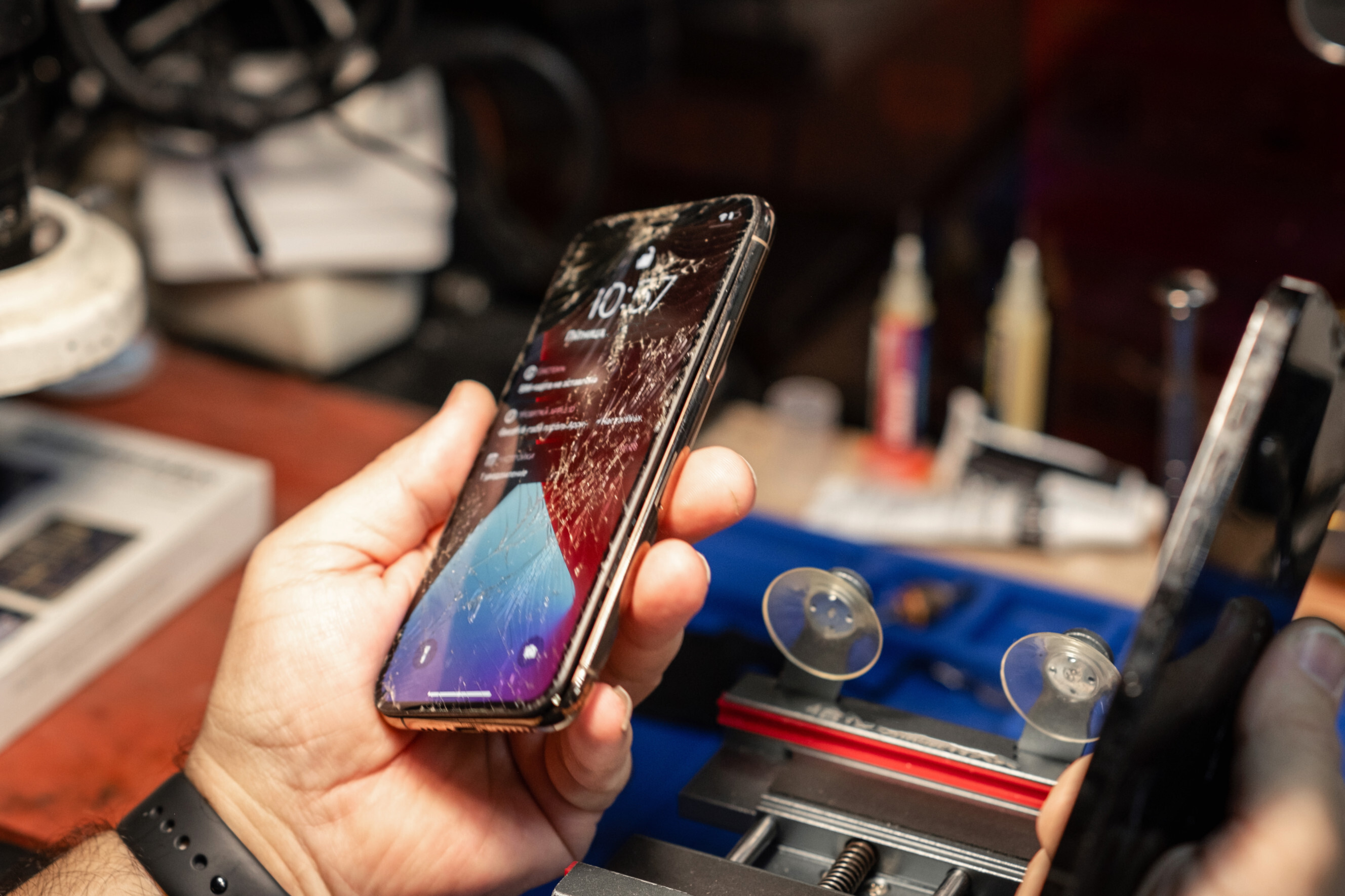 Technician examining a cracked iPhone screen before starting a replacement, highlighting professional iPhone screen replacement experts near you.