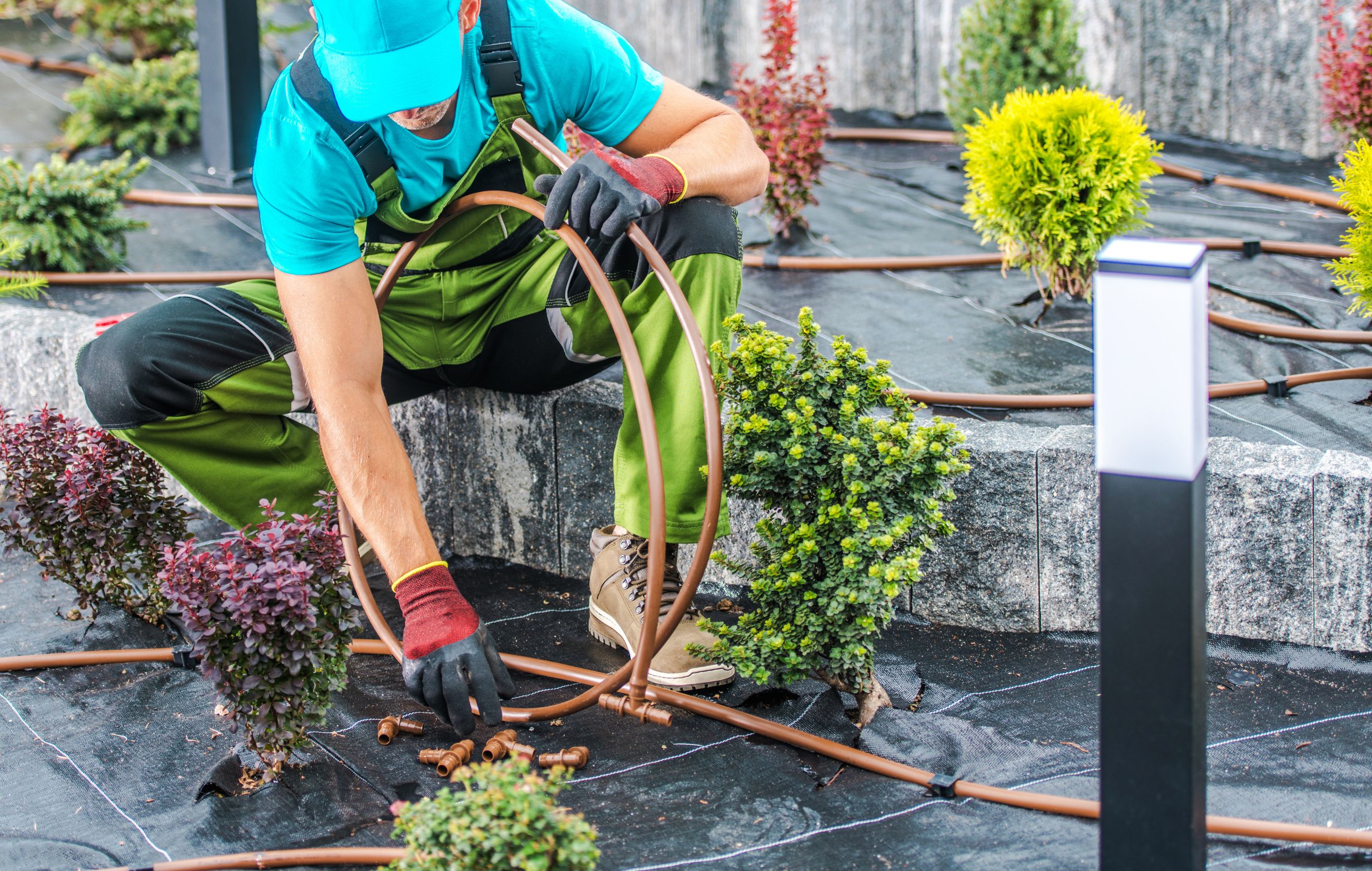 Professional gardener with pipes in his hand performing sprinkler repair.