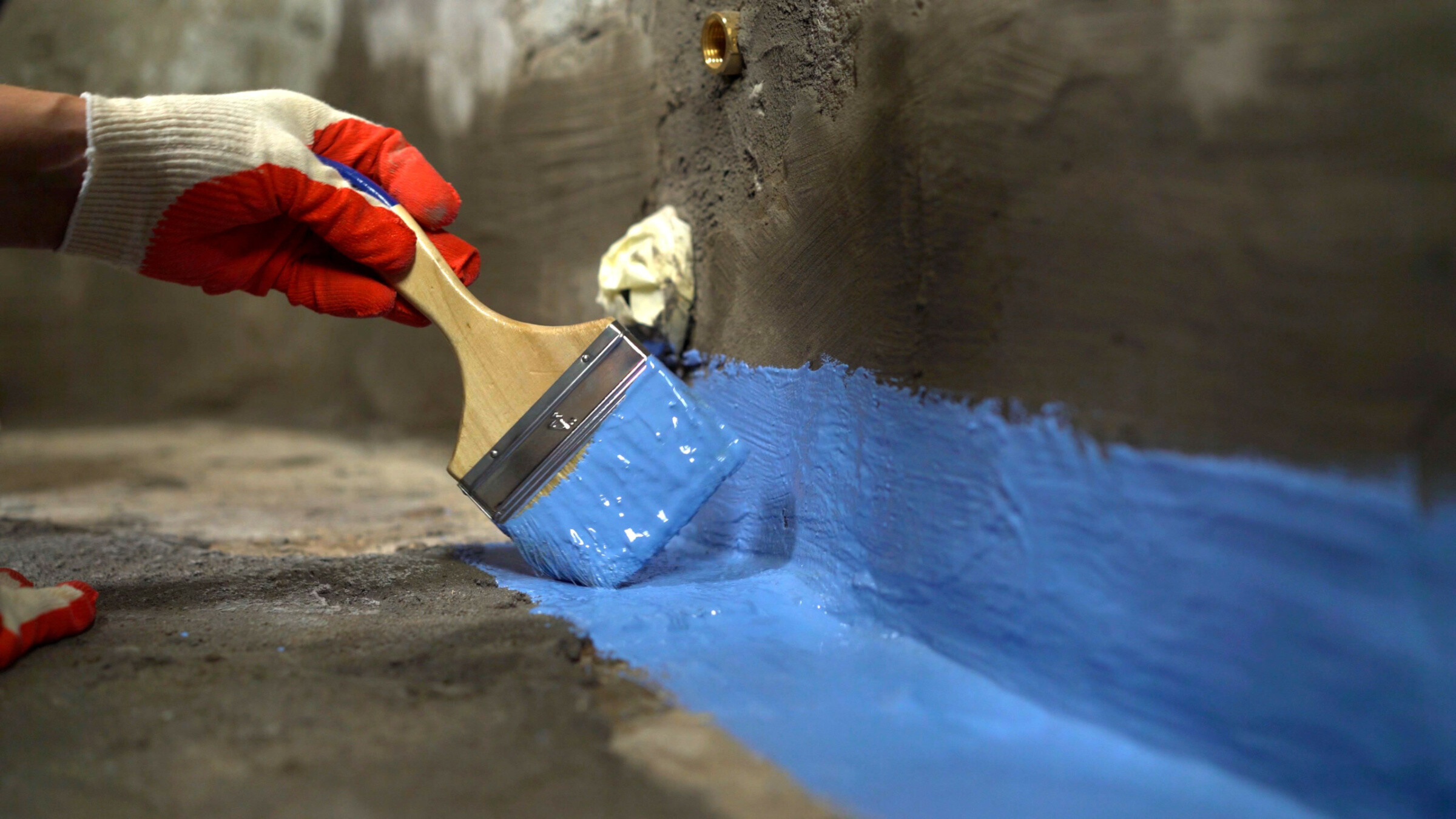 The master puts damp proofing on a concrete floor with a brush.