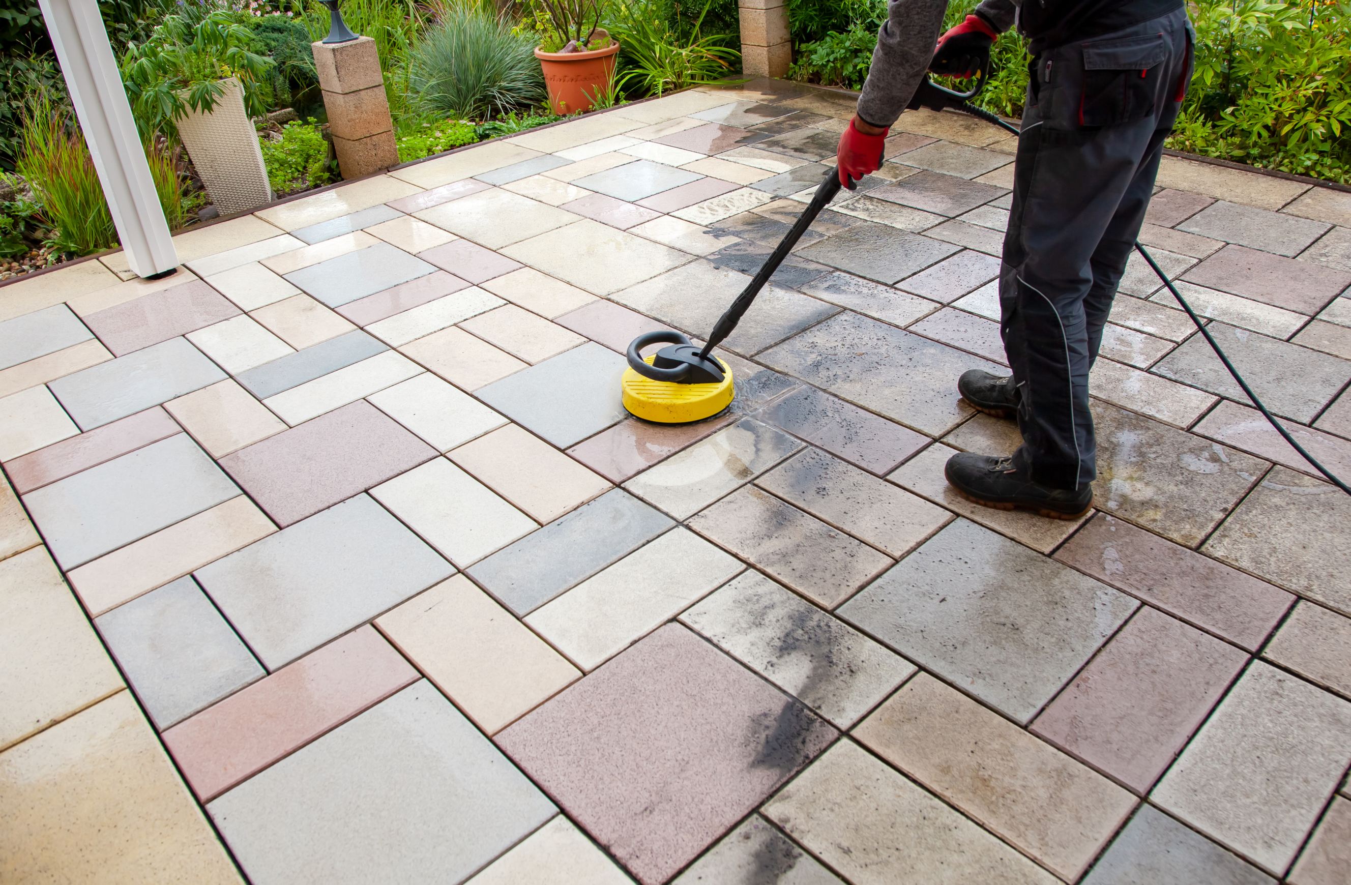 A worker cleaning the patio with professional tools.