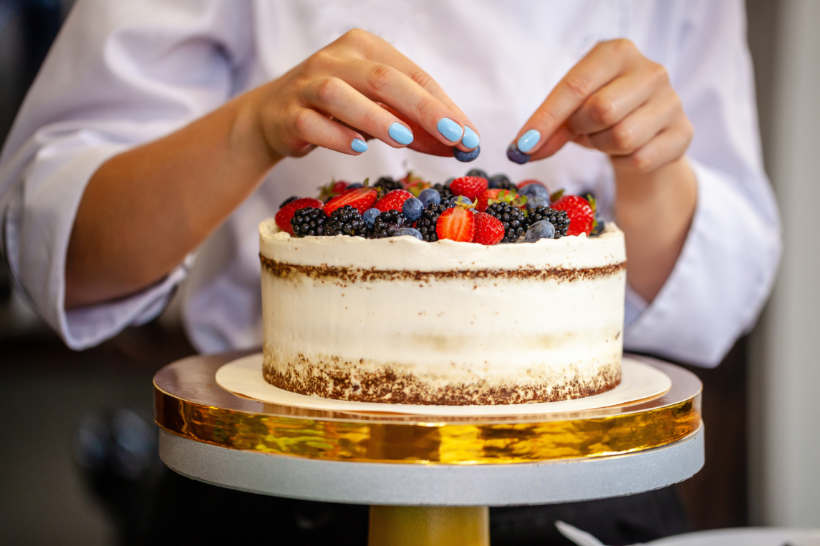 Baker vs pastry chef — Chef adding creative touches to a fruit-topped cake