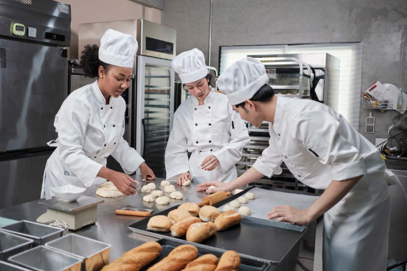 Baker vs pastry chef — Bakers collaborating to maintain production pace in the kitchen