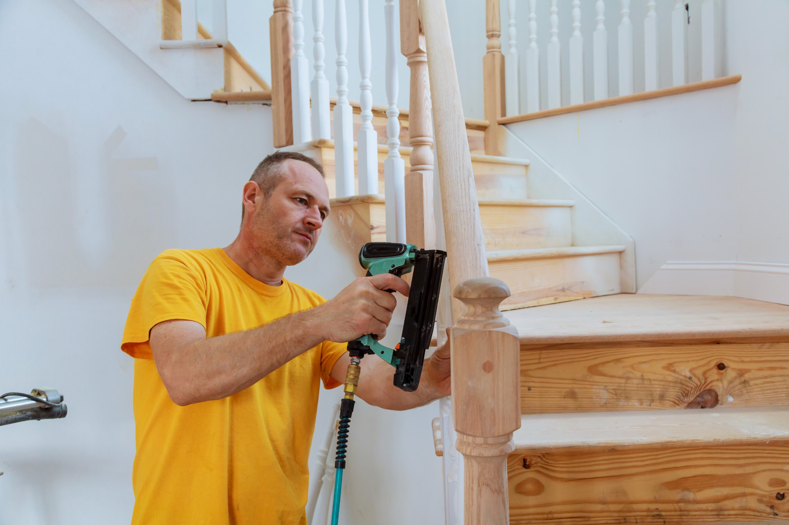 Experienced balustrading contractor installing wooden balusters on a staircase, highlighting professional balustrading services near you.