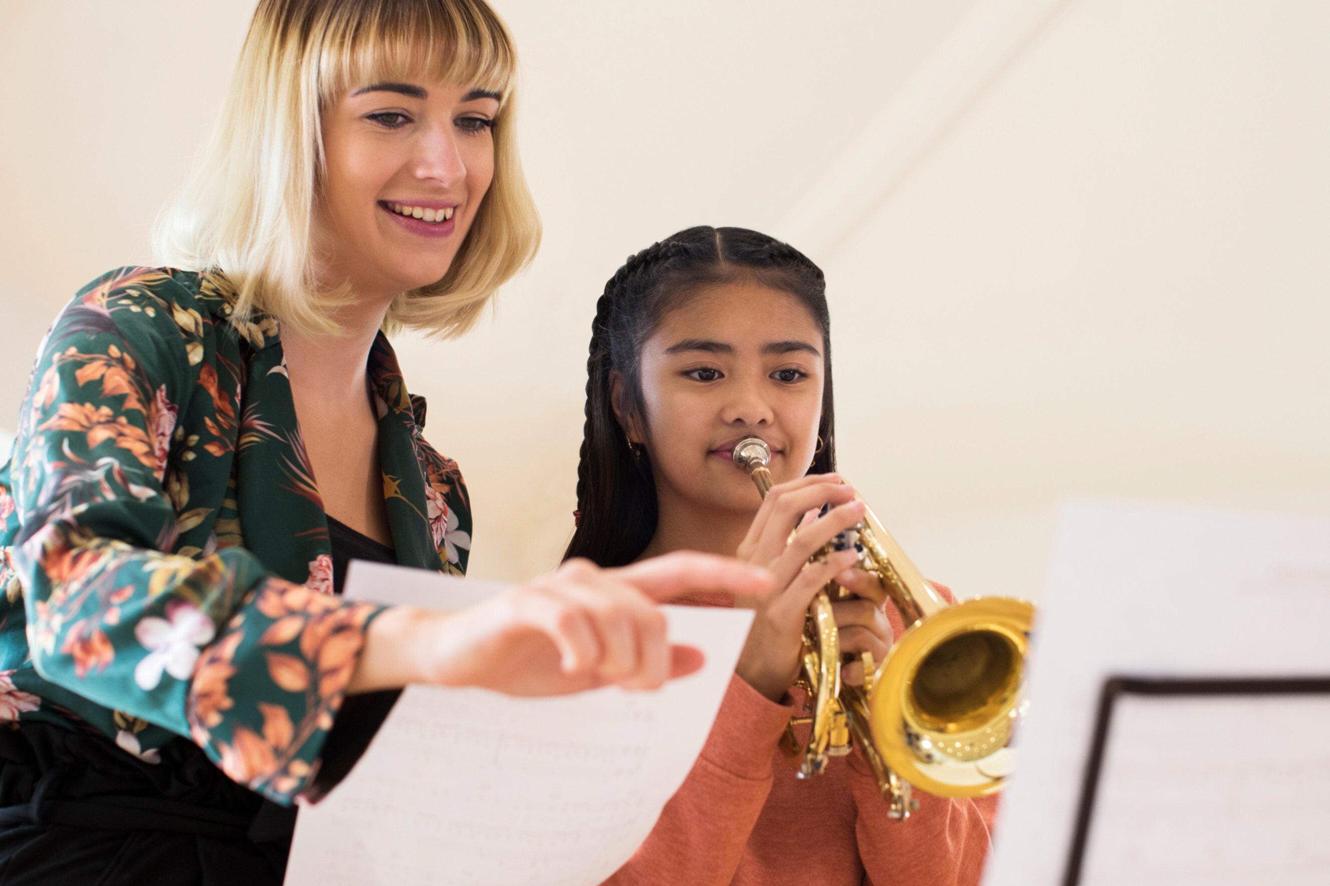 Music teacher guiding a young student playing the trumpet, highlighting professional music lessons near you.