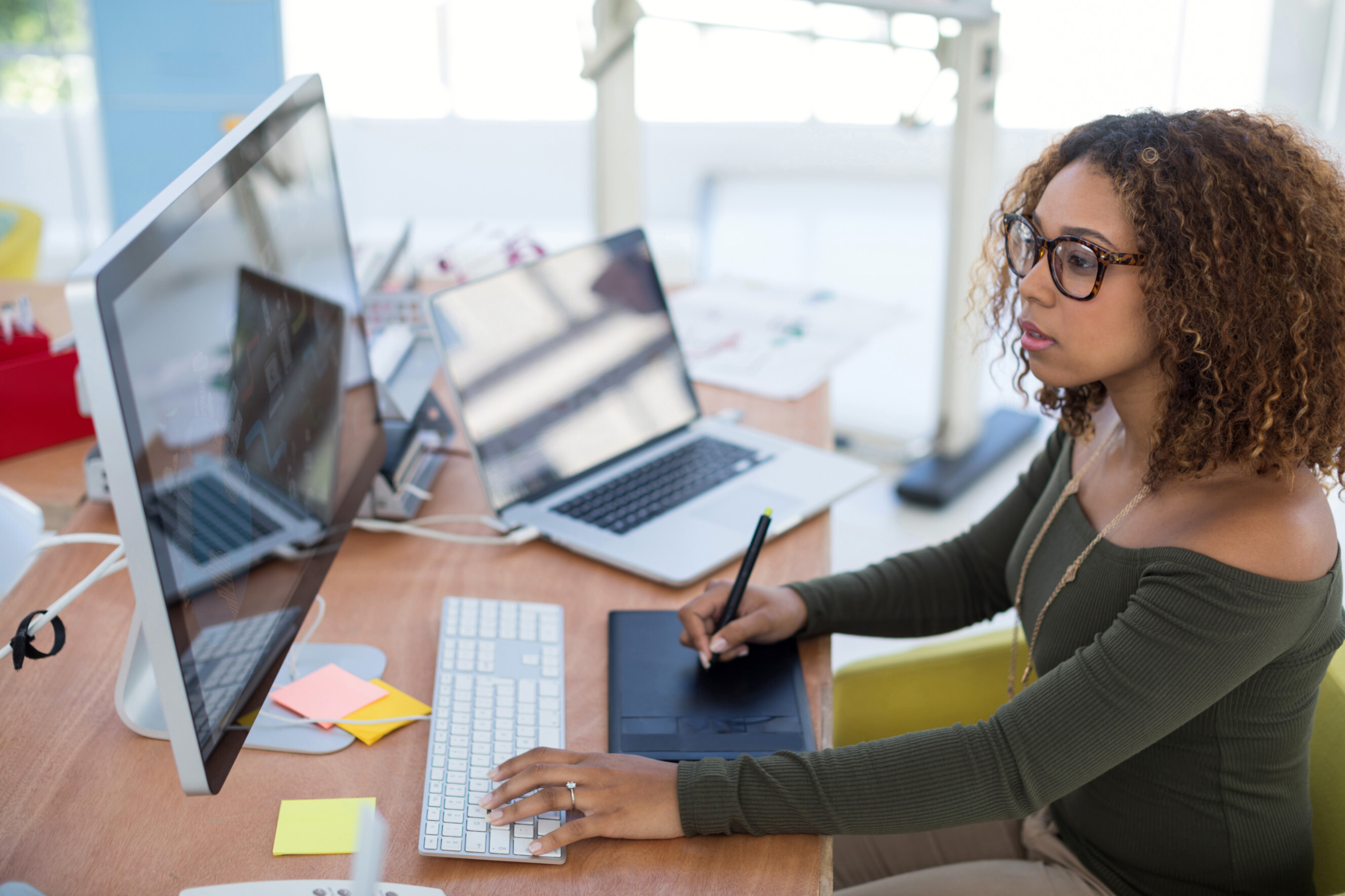 Graphic designer working on a digital tablet and computer in a creative workspace, highlighting professional graphic design services near you.