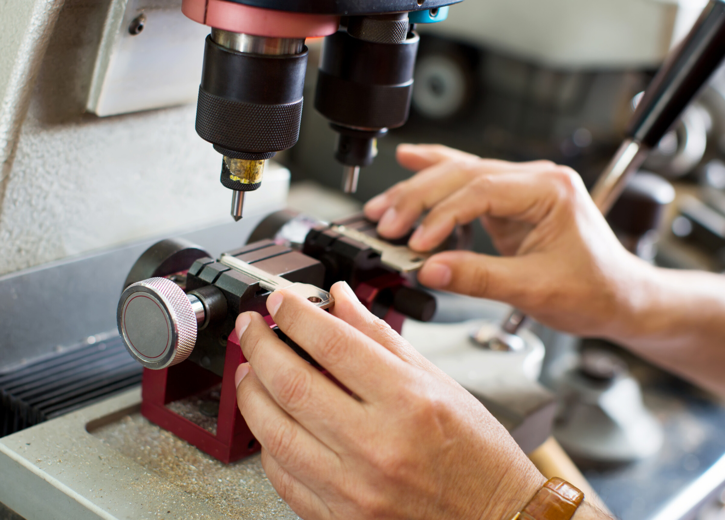 Professional worker cutting duplicates of keys on laser machine at workshop