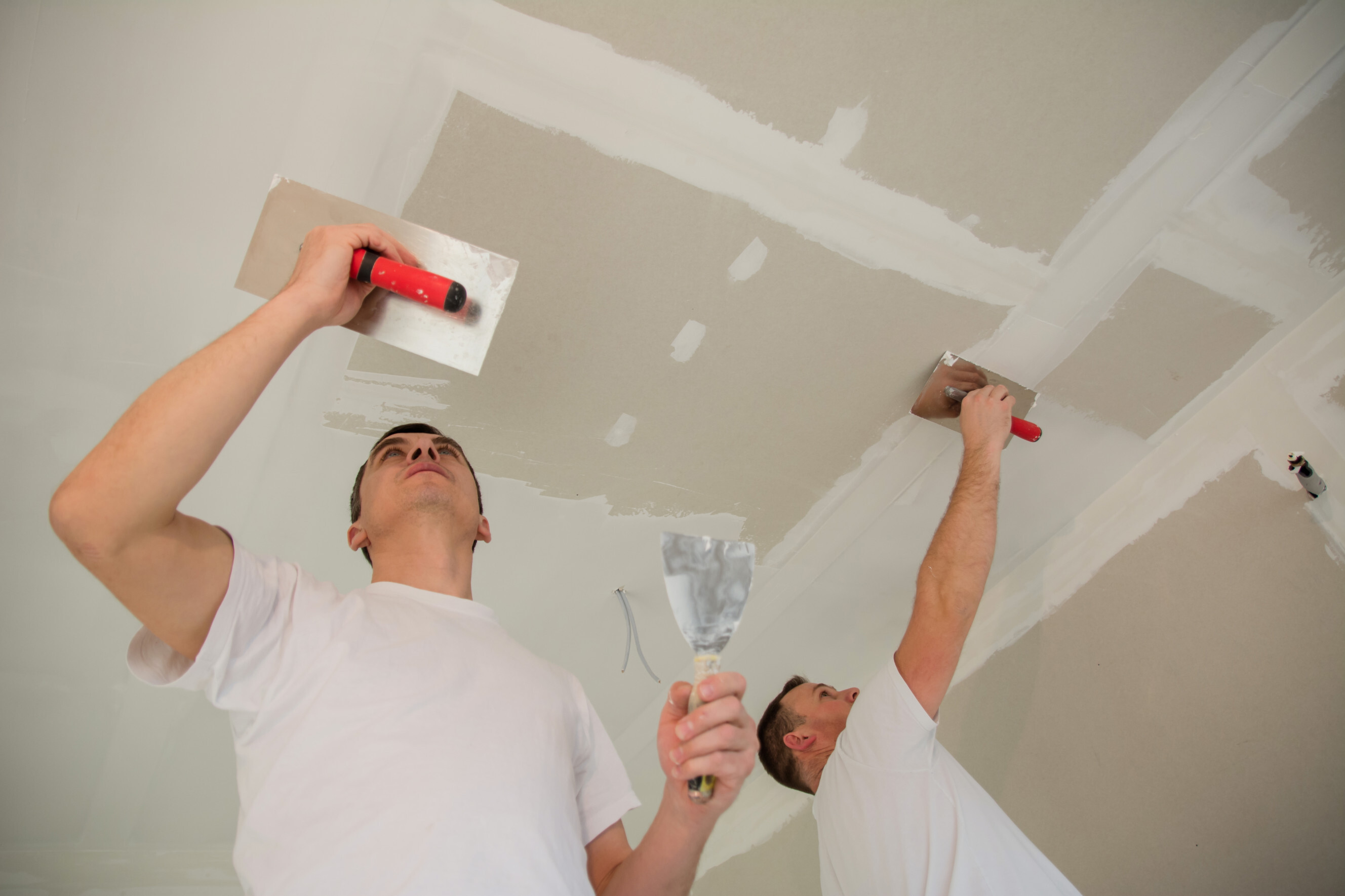 Experienced Gyprock installers applying plaster to a ceiling, showcasing professional Gyprock installation services near you.