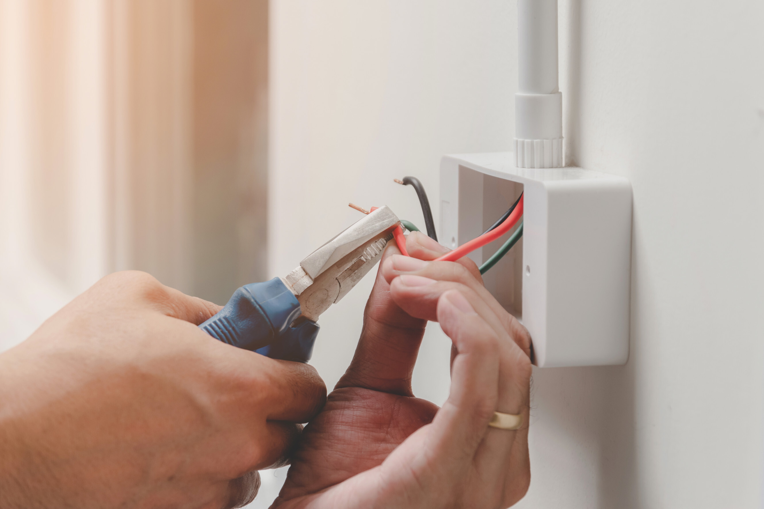 Certified electrician installing a new power point, carefully handling electrical wires with pliers, representing expert power point installation services near you.