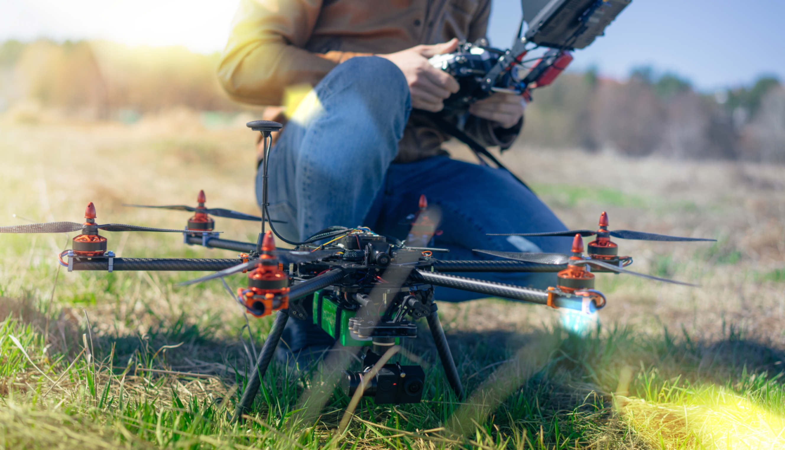 Drone pilot adjusting a professional aerial drone in an outdoor setting.