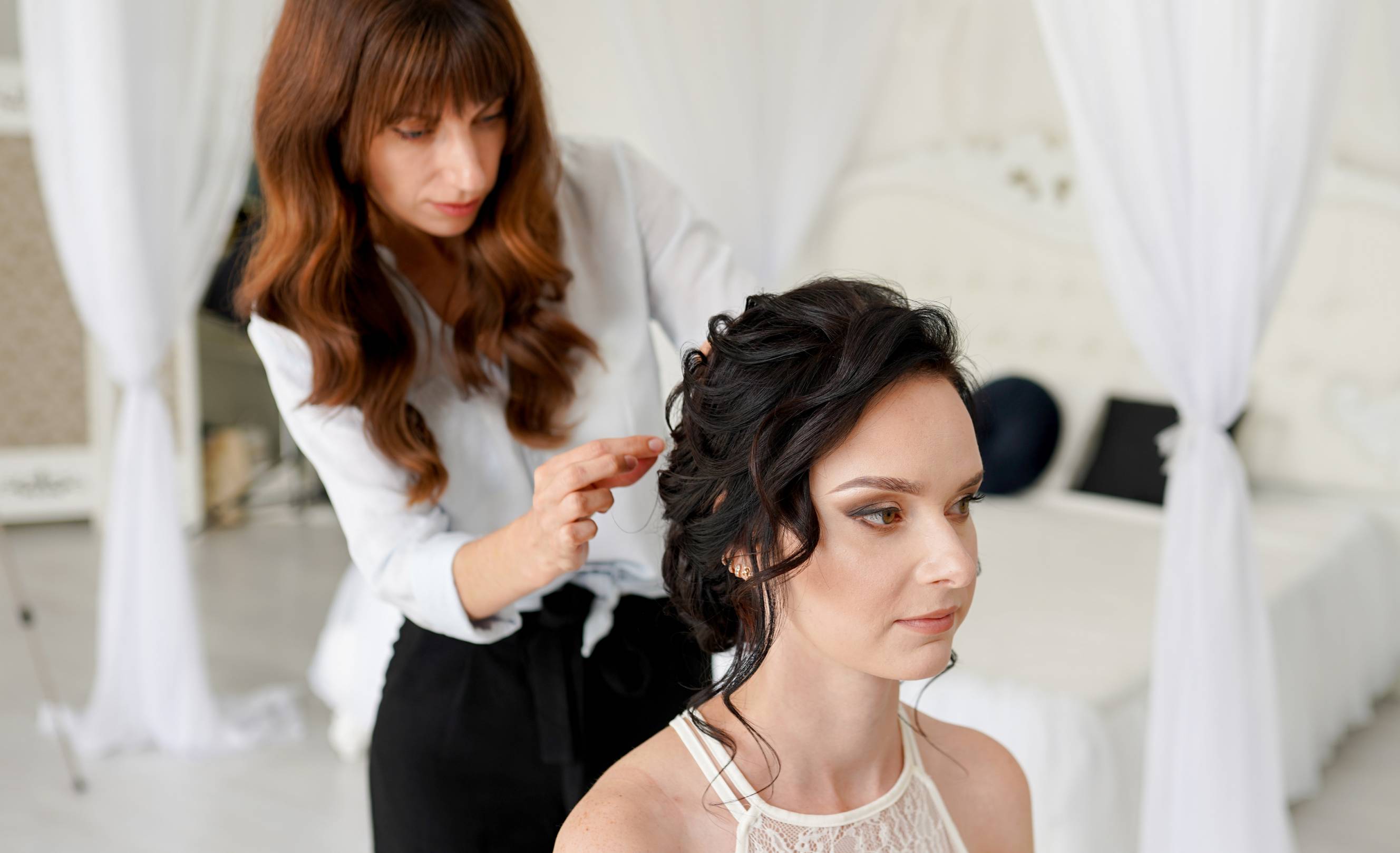 A wedding hair stylist doing professional hair styling on a bride for her wedding day