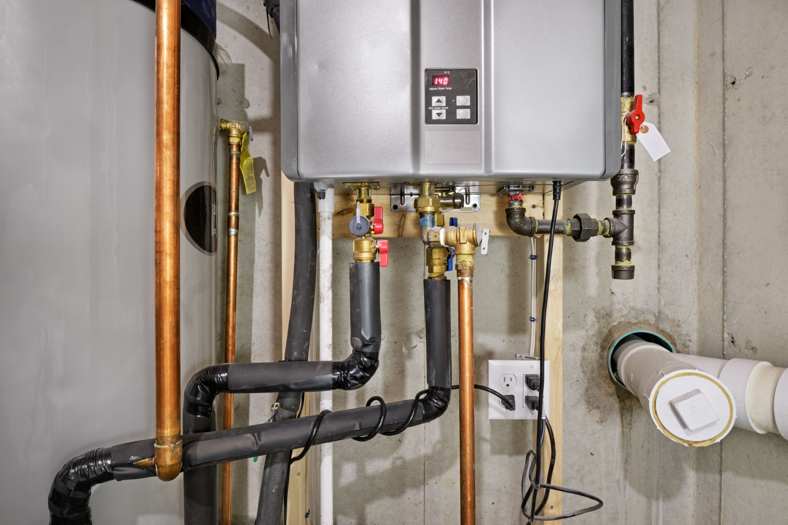 Tankless hot water heater connected to a recirculation system and storage tank signifying tankless water heater repair.