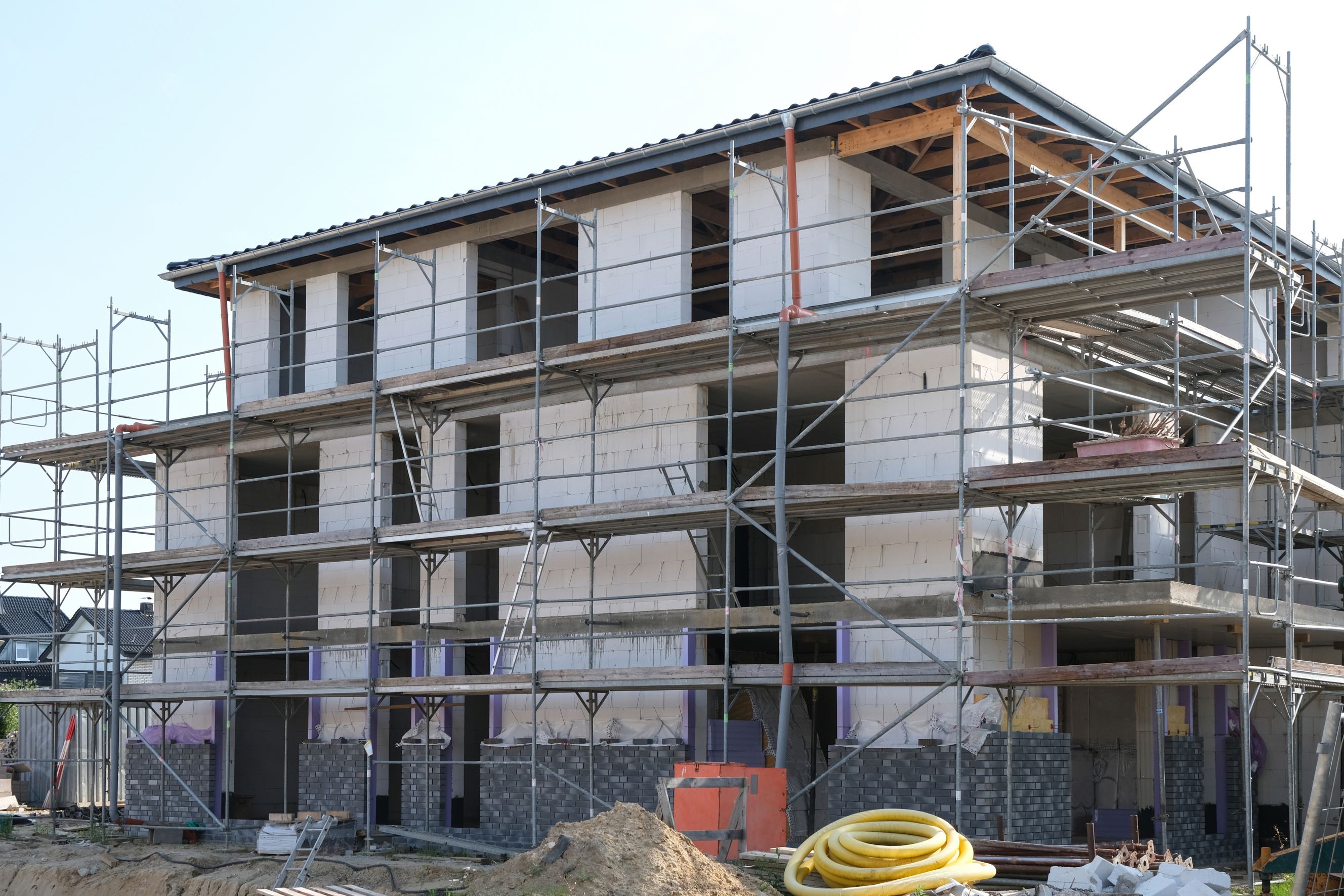 A construction site with equipment, tools and materials and a scaffolded shell of a house with plenty of copy space signifying scaffolding rental near me.