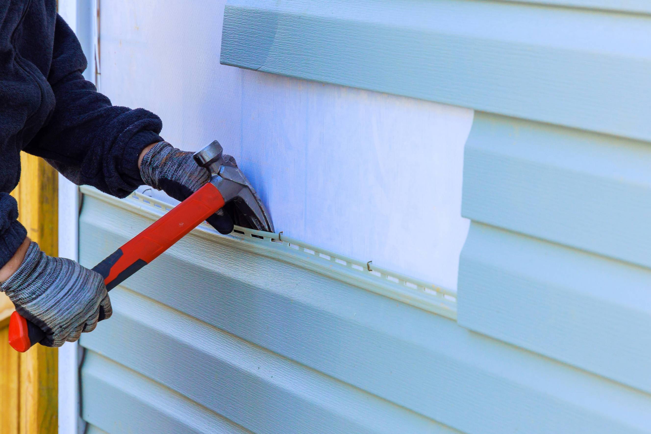 A handyman doing weatherboard repair near me on the exterior wall of a house