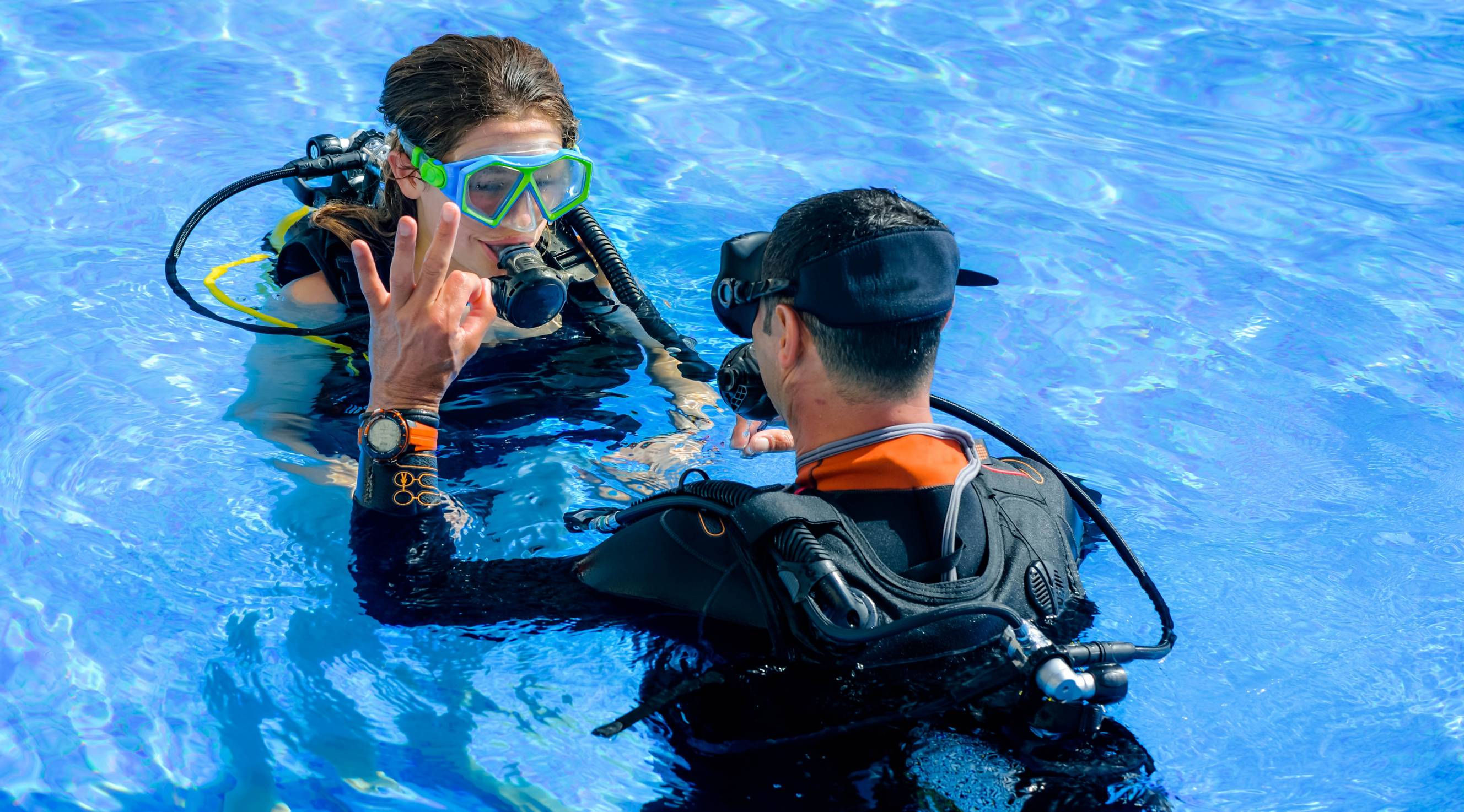 Experienced scuba diver teaching diving lessons near me to a female client in a swimming pool