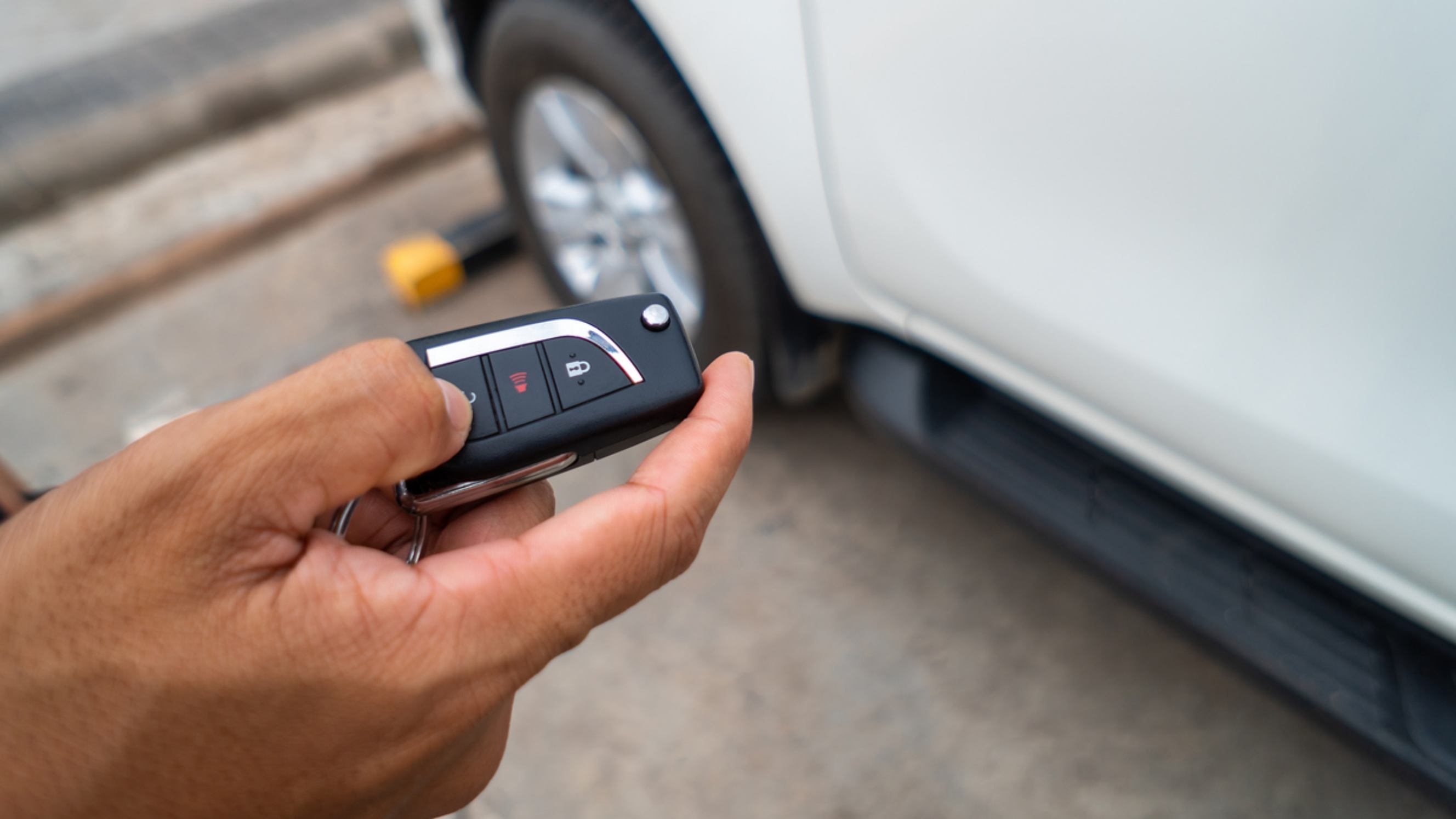 A person using a car key fob to activate the car alarm system for troubleshooting or repair near you