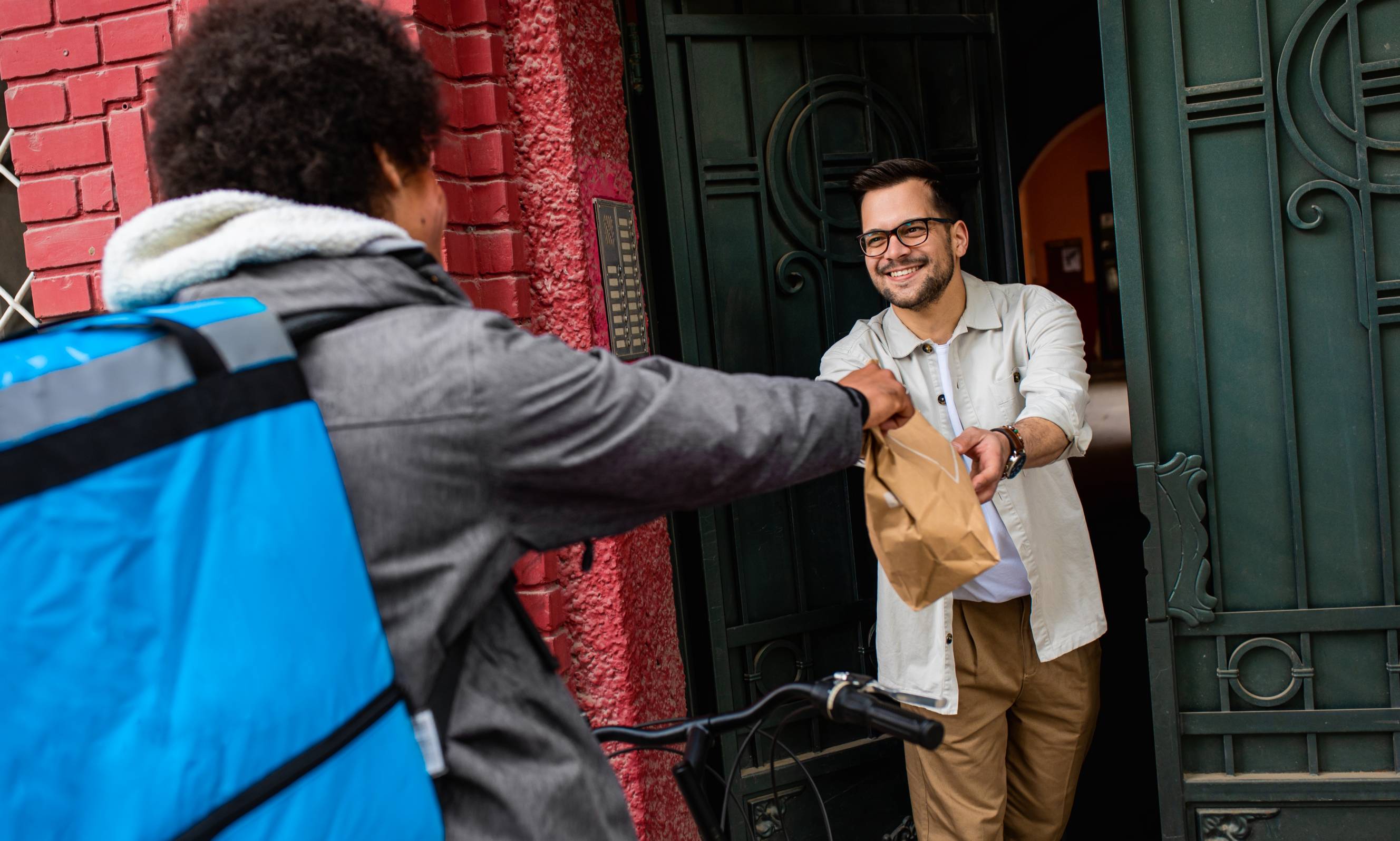 A man gets food delivery near me from a local Tasker on a bicycle.