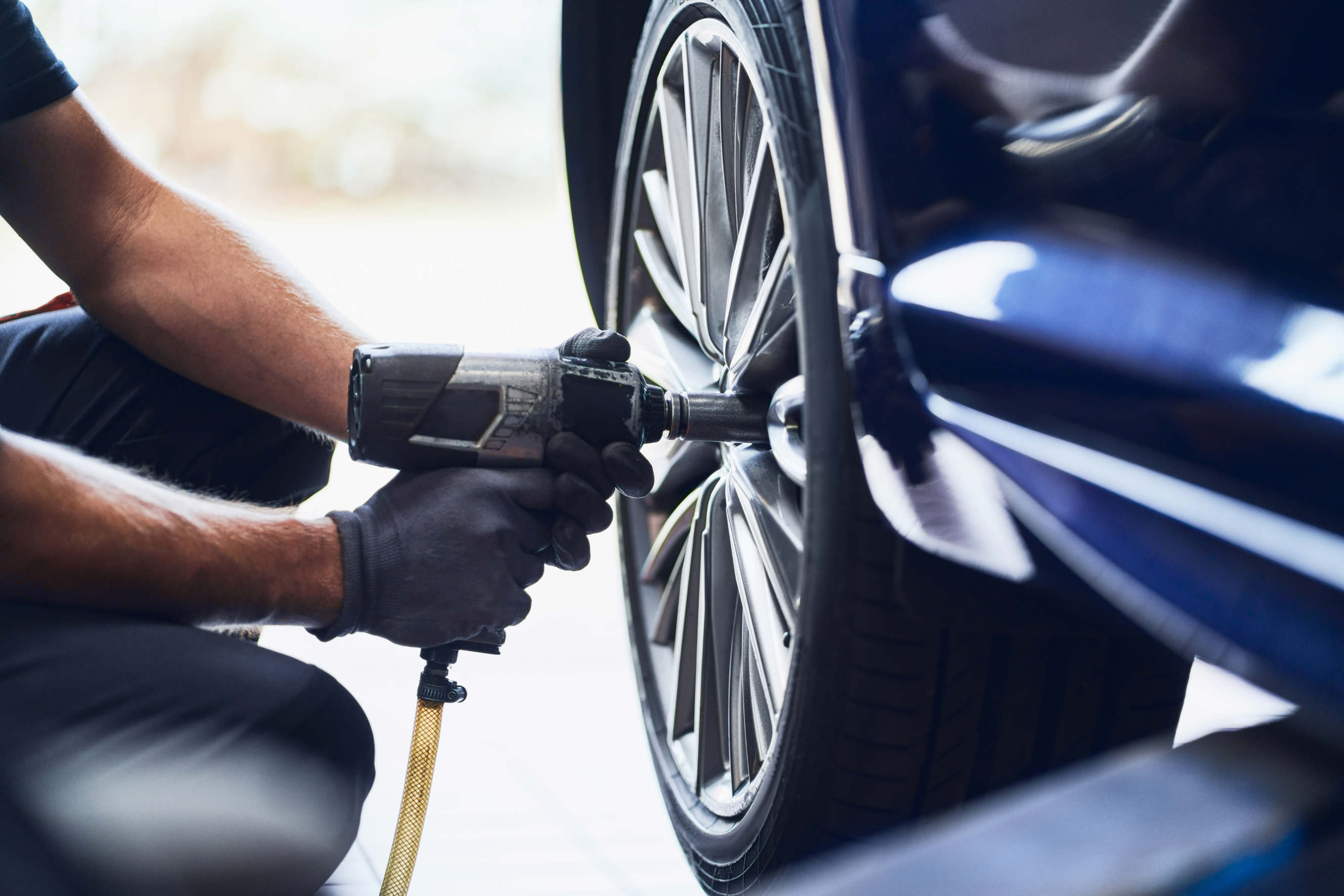 A skilled technician using an impact wrench to restore a car’s alloy wheel.