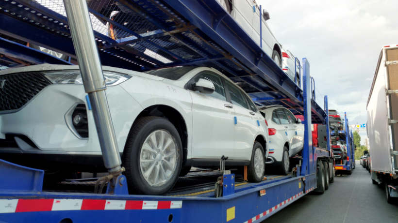 Car transport cost - Open carrier truck transporting large SUVs