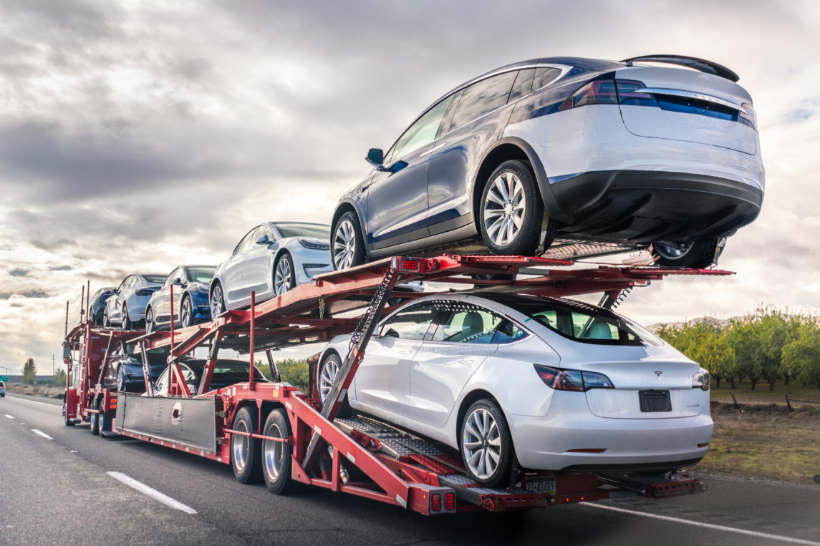 Car transport cost - A large transport truck carrying multiple vehicles on an open carrier