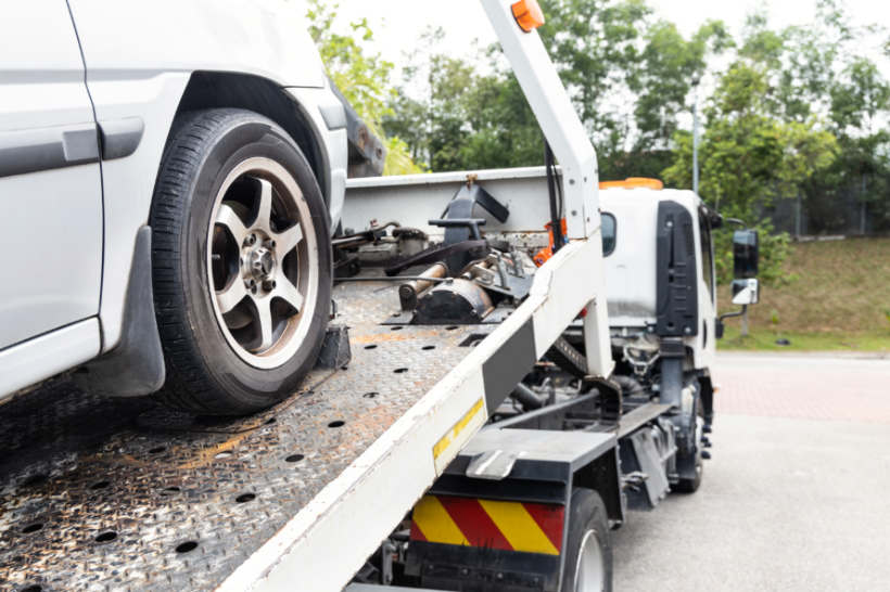 Car transport cost - A tow truck transporting a non-operational car