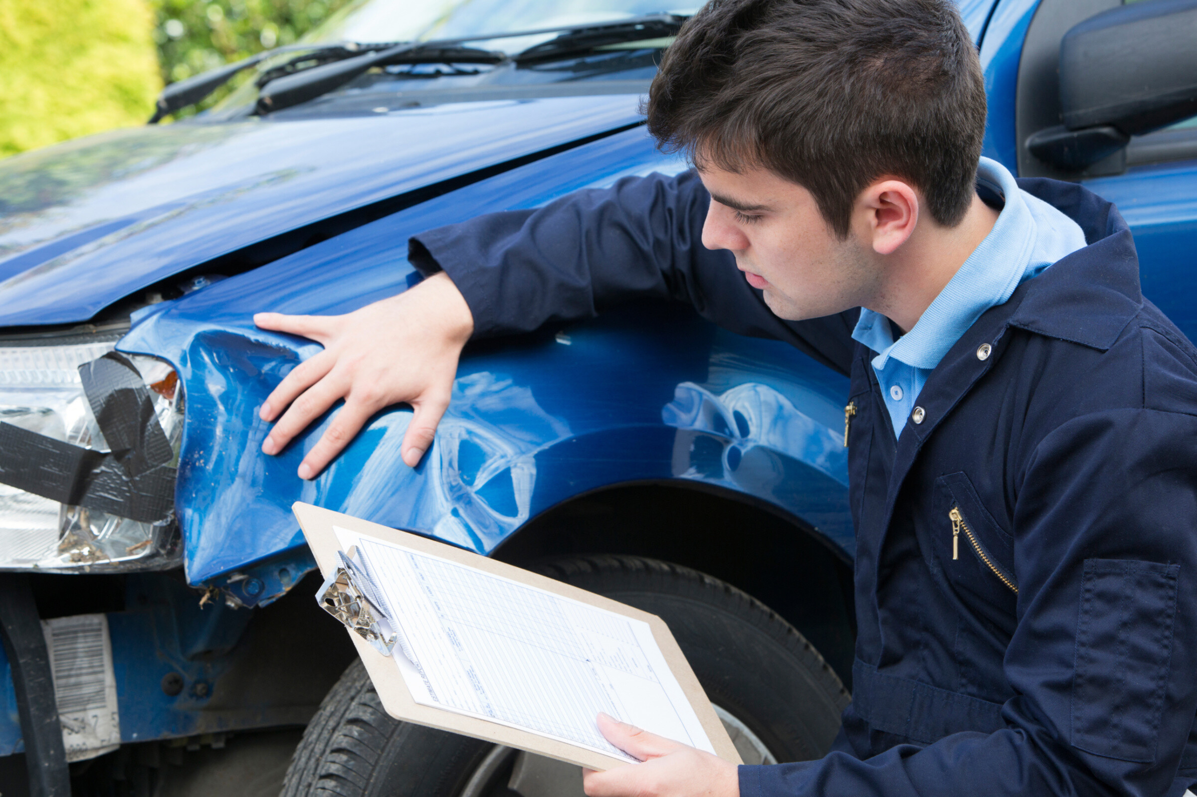 A mechanic inspecting a damage car for a cost estimation and report.