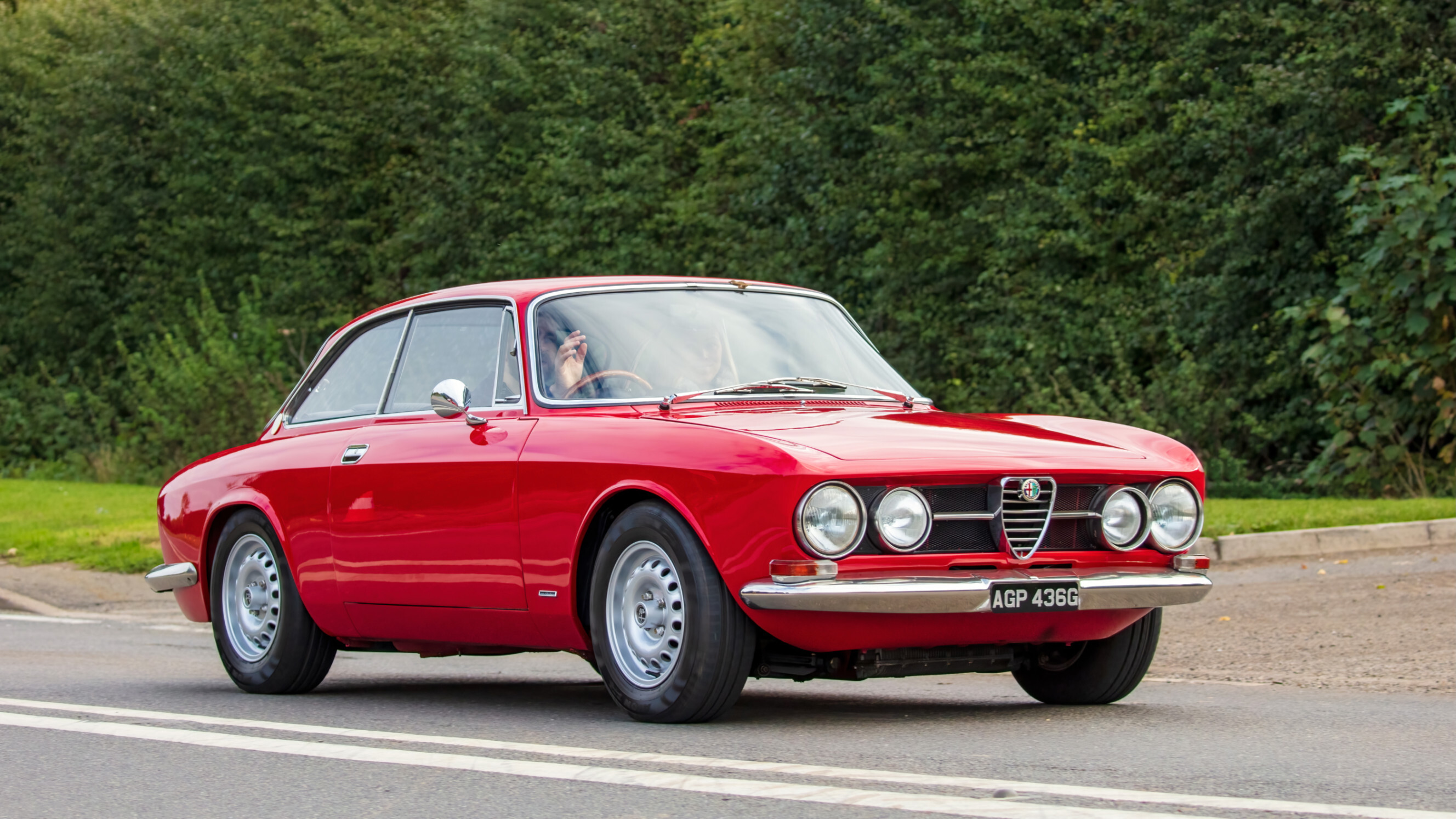 A red Alfa Romeo driving down the road