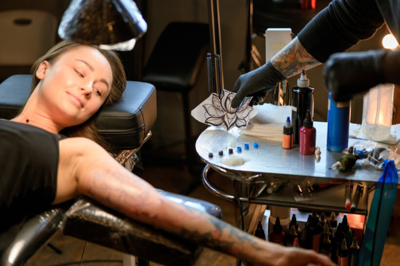 how much do tattoos cost - Woman relaxing while getting a detailed sleeve tattoo in a professional studio