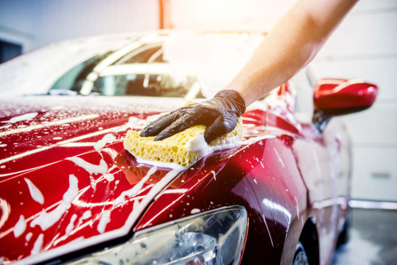 Car wash cost - Hand detailing a car with a sponge during an exterior wash.