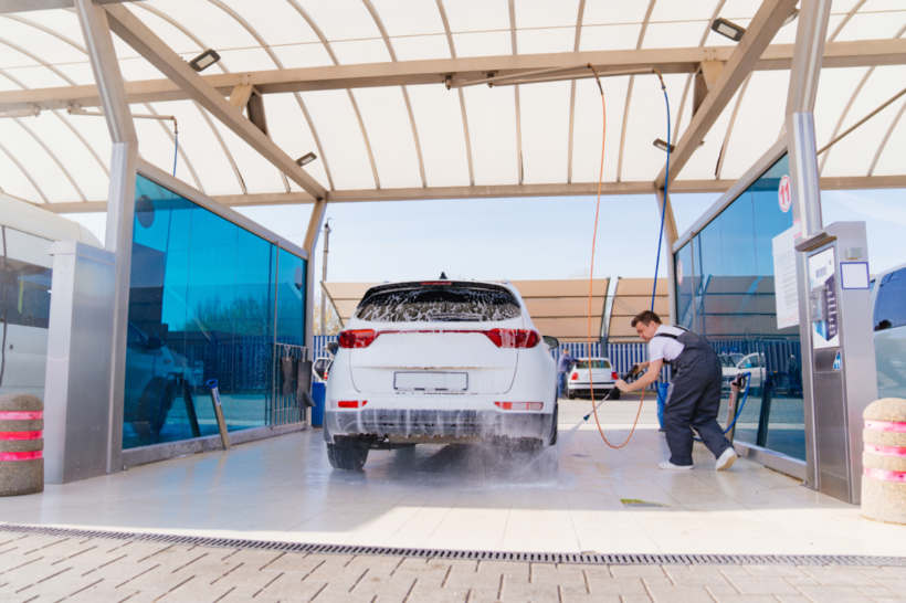  Car wash cost - a white car covered in soap being washed at an outdoor facility