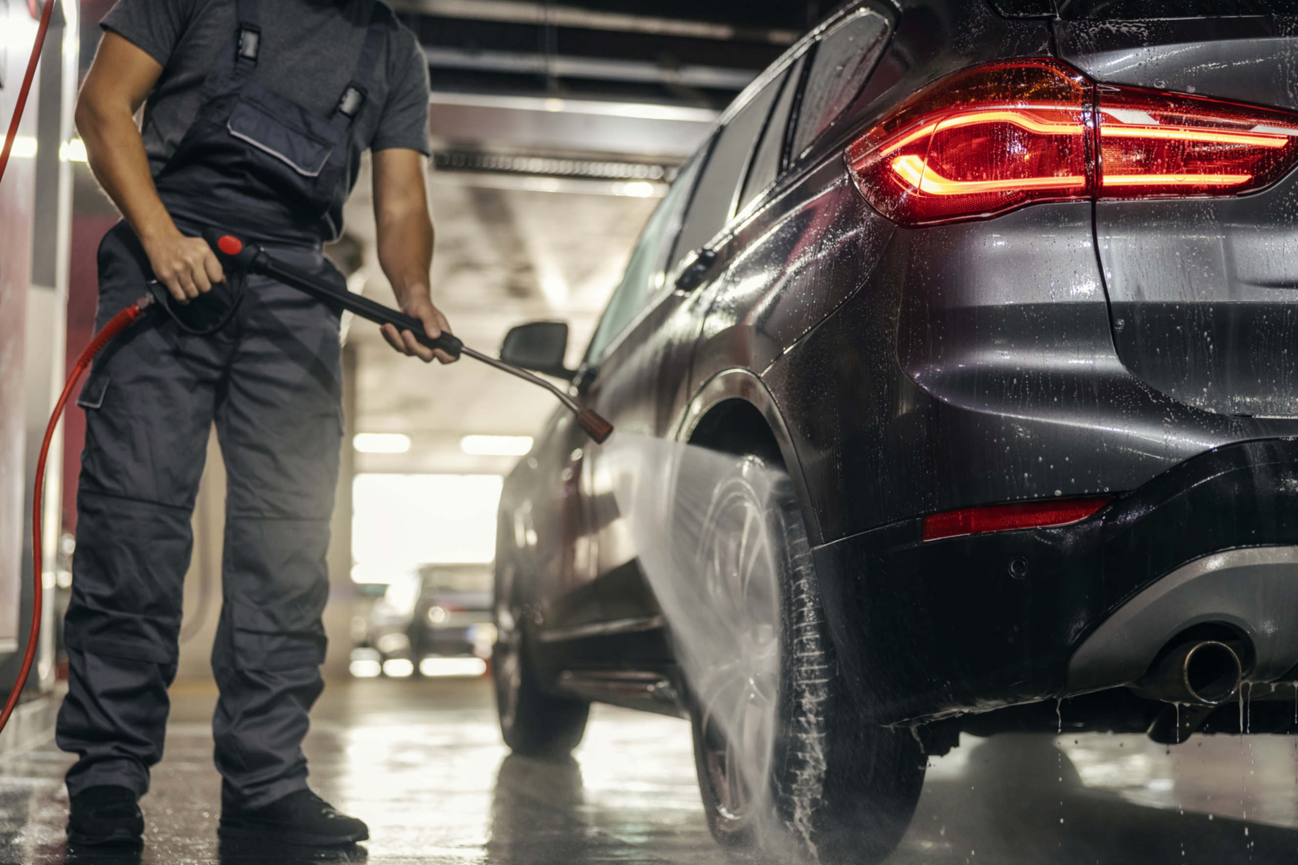 A black SUV getting a deep clean with a pressure washer.