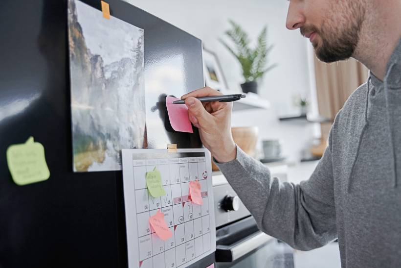 personal chef cost - a man writing on a refrigerator sticky note