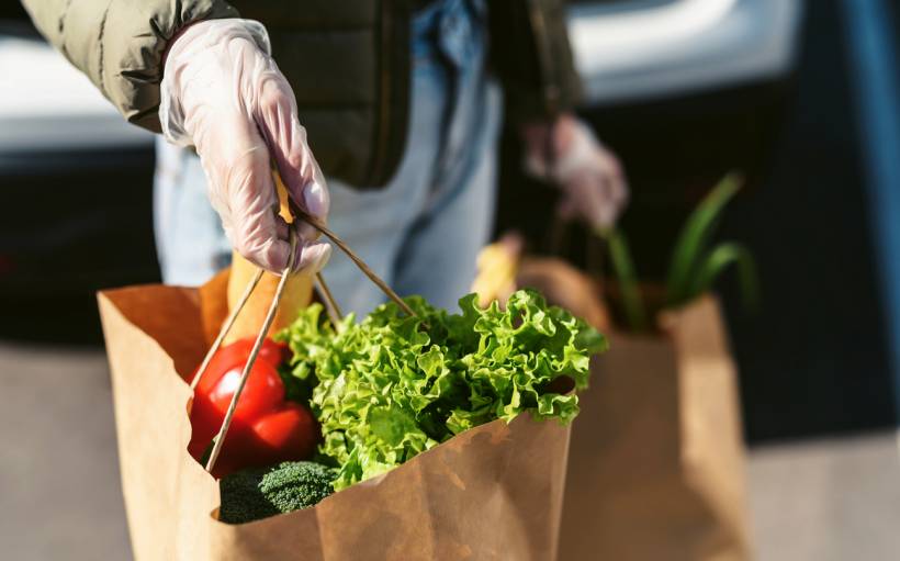 personal chef cost - a young woman with grocery bags from a supermarket, car trunk at background