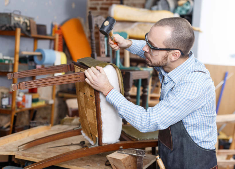 Cost to reupholster a chair  - A furniture maker securing upholstery to a wooden chair