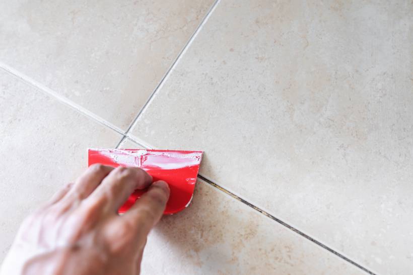 cost to install tile floor - a man regrouting a tile floor