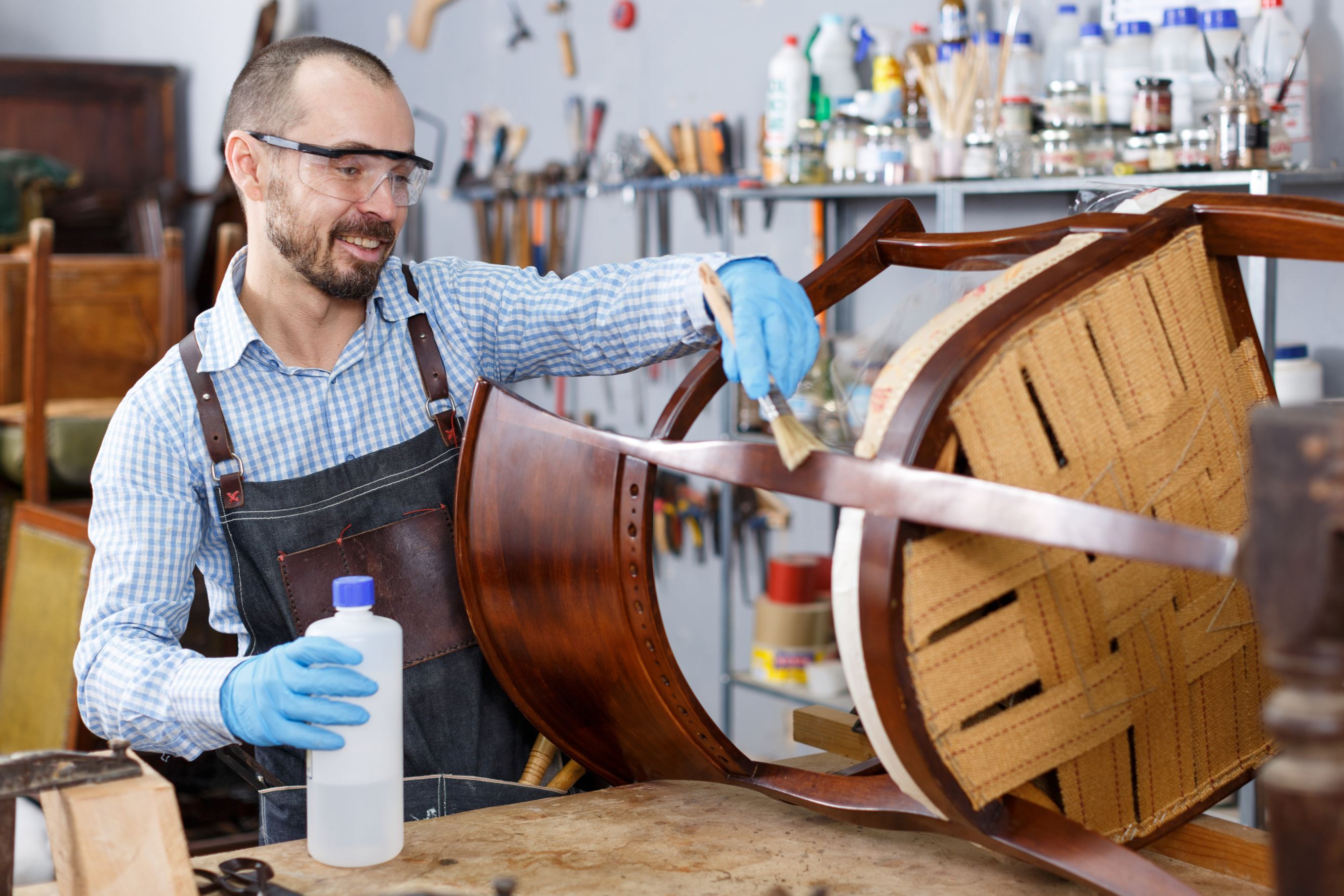 A professional restorer varnishing vintage chair in workshop symbolizing antique restoration near me.