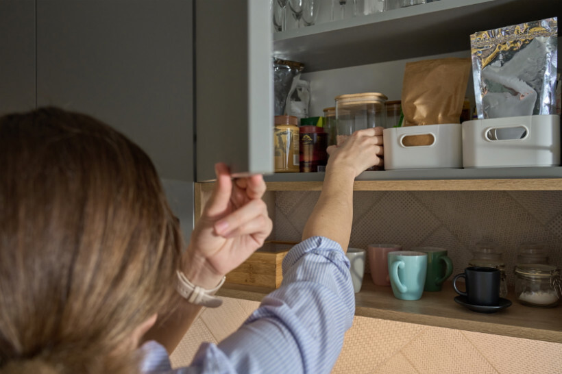 how to eradicate pantry weevils - woman checking pantry items stored in labeled containers and jars