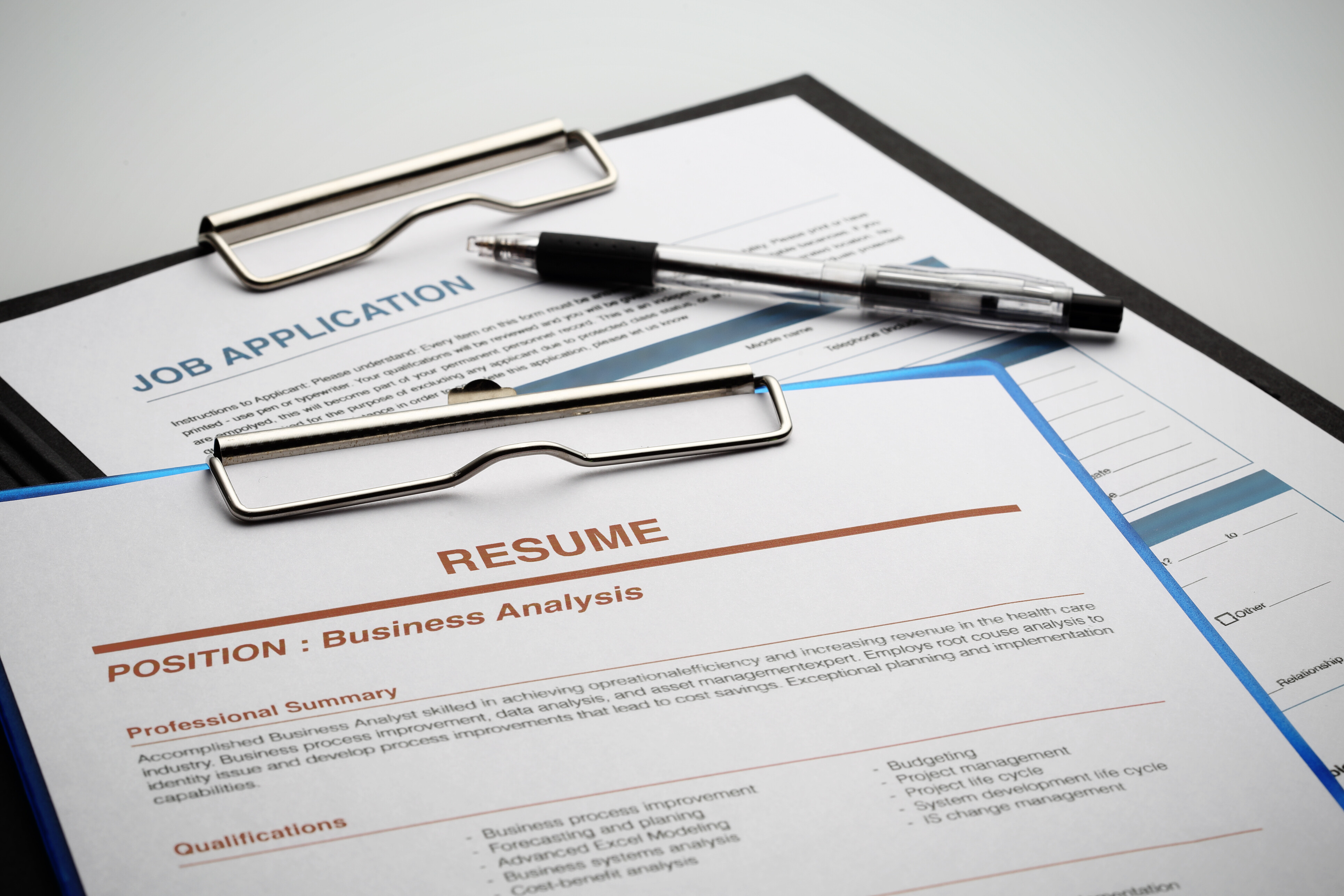 How to write a resume – business analyst resume and job application on clipboard