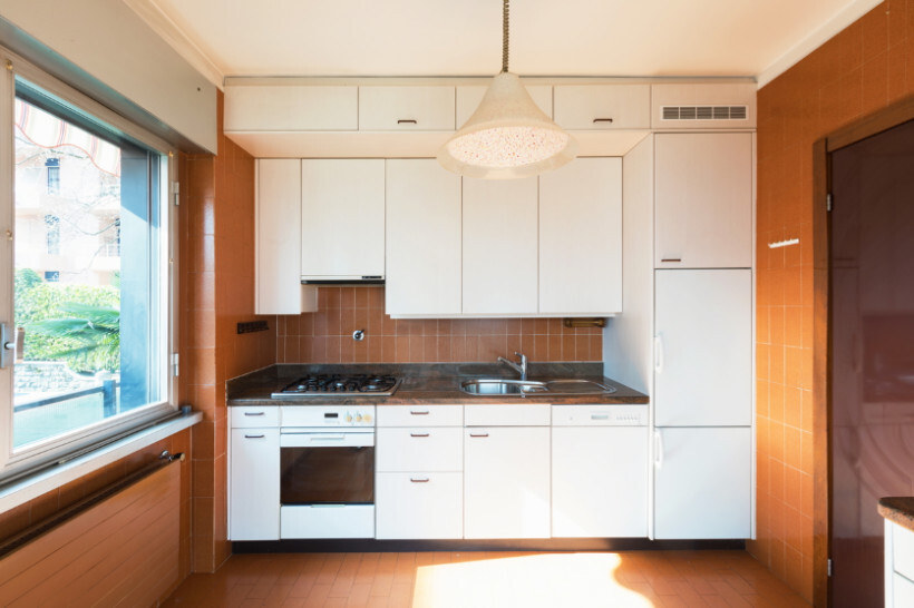 IKEA kitchen cost - A dated kitchen interior with white cabinets and orange tile walls awaiting remodel