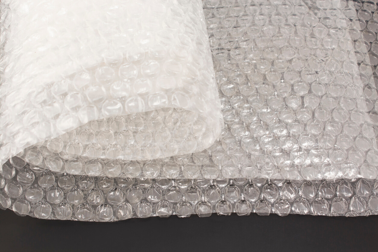 Close-up of a roll of transparent bubble wrap on a flat surface. - bubble wrap vs packing paper