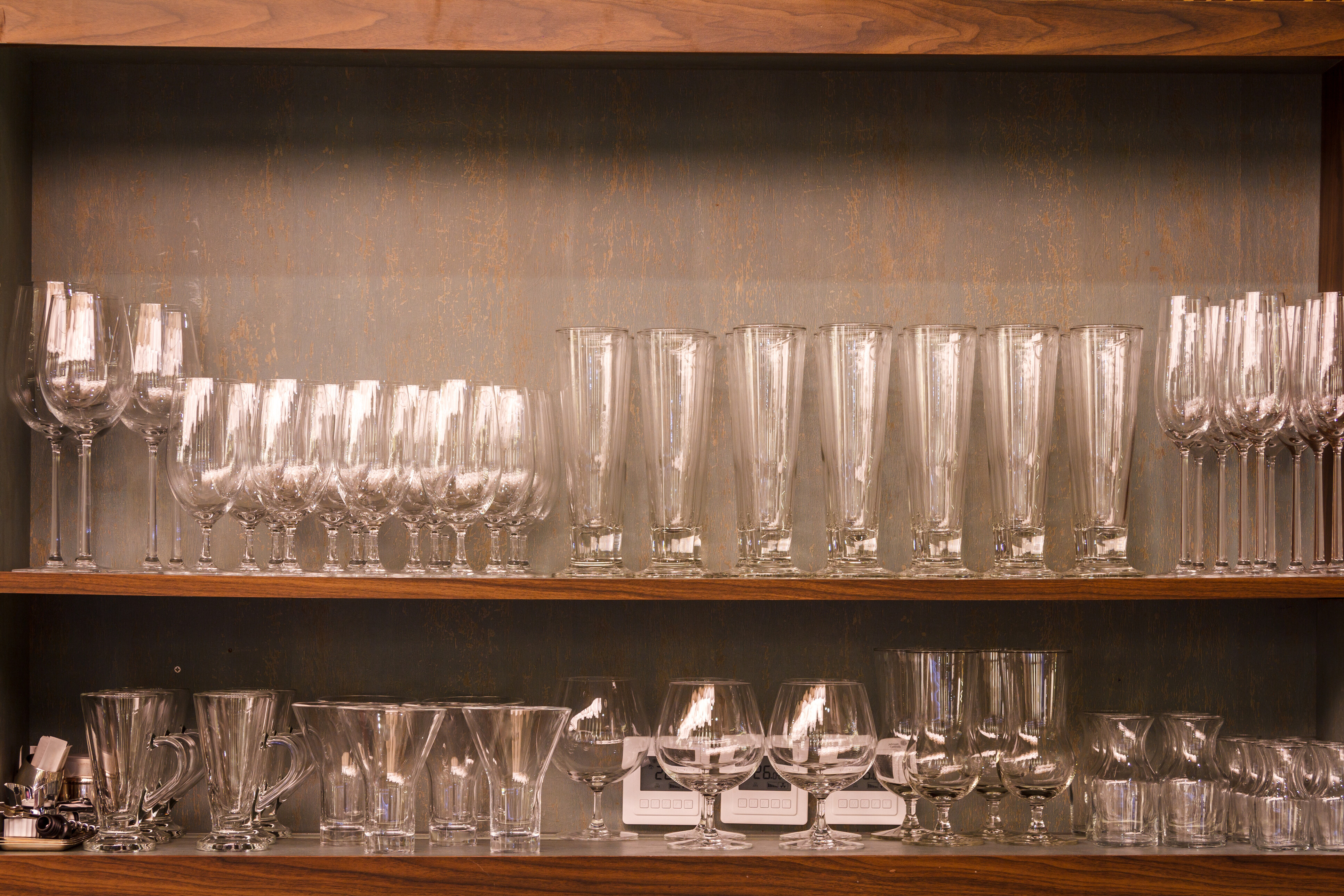 Assorted glassware neatly arranged on wooden shelves.